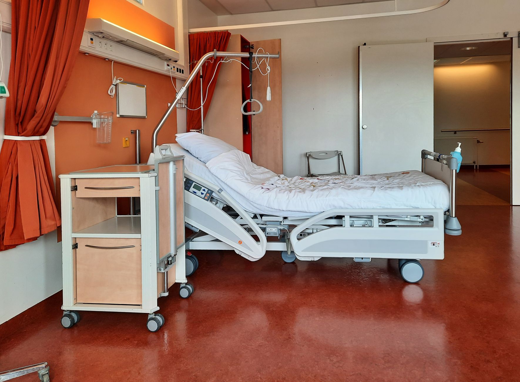 Calm hospital room with a pregnant woman lying on a bed, a monitor displaying heart rate and a small bedside table with a glass of water