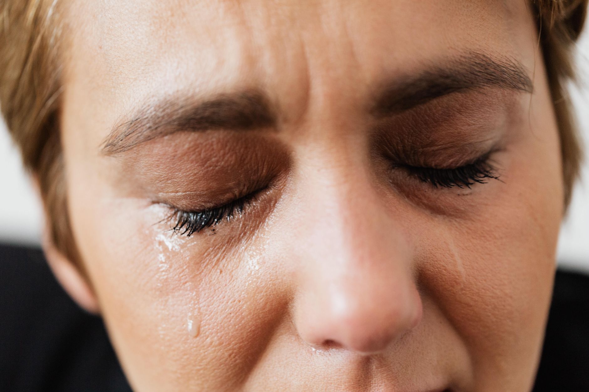 A woman sitting on a bed with a weighted blanket, looking exhausted but supported