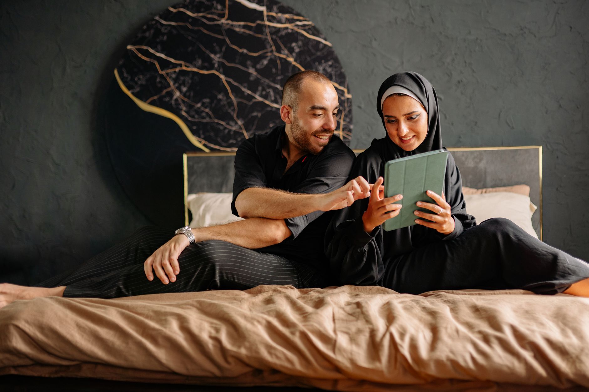 A couple with their toddler on their bed, smiling tiredly