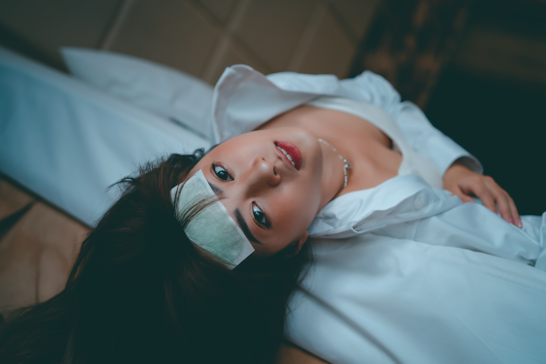 A woman lying in bed with a cold compress on her forehead