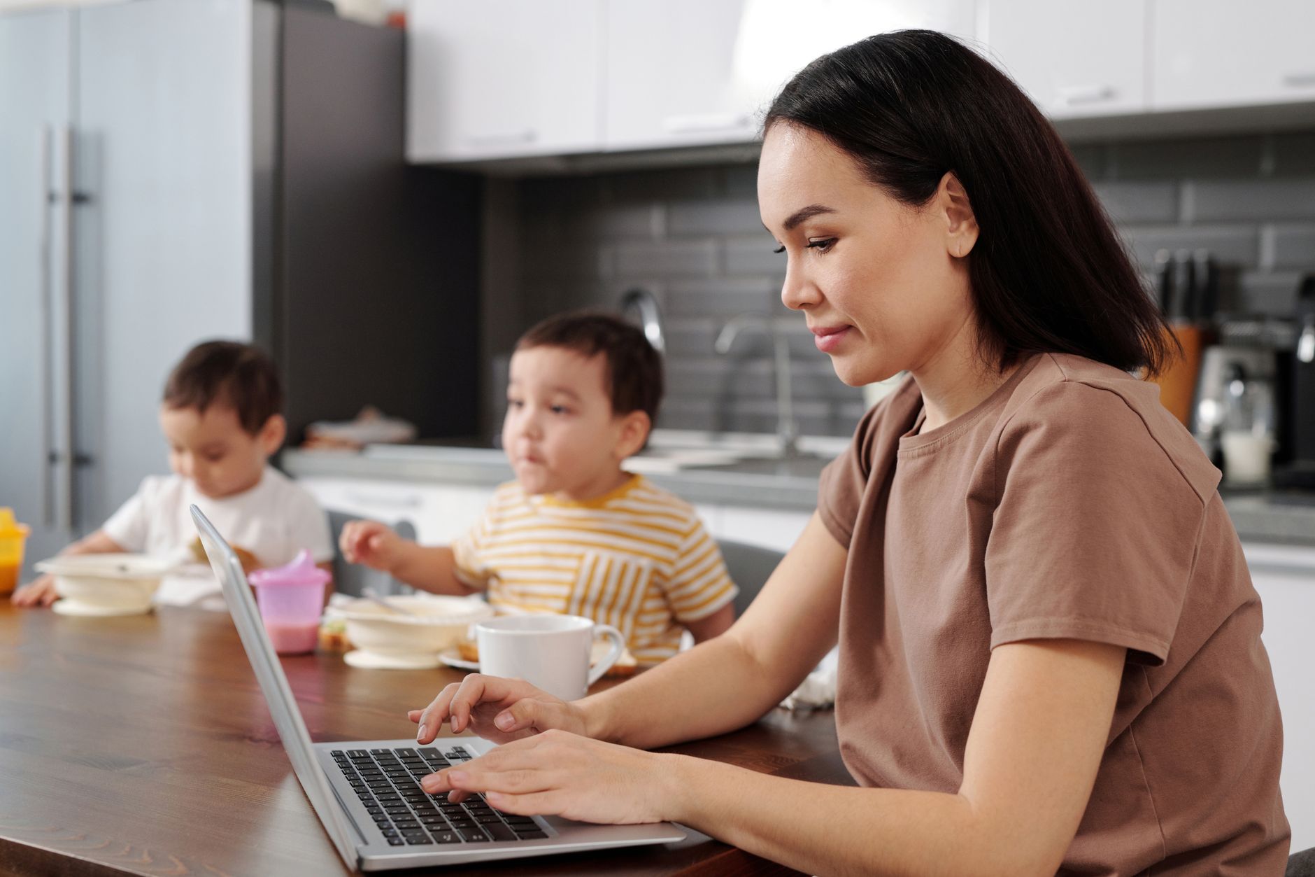 A mom quickly tidying up the kitchen counter while holding a baby