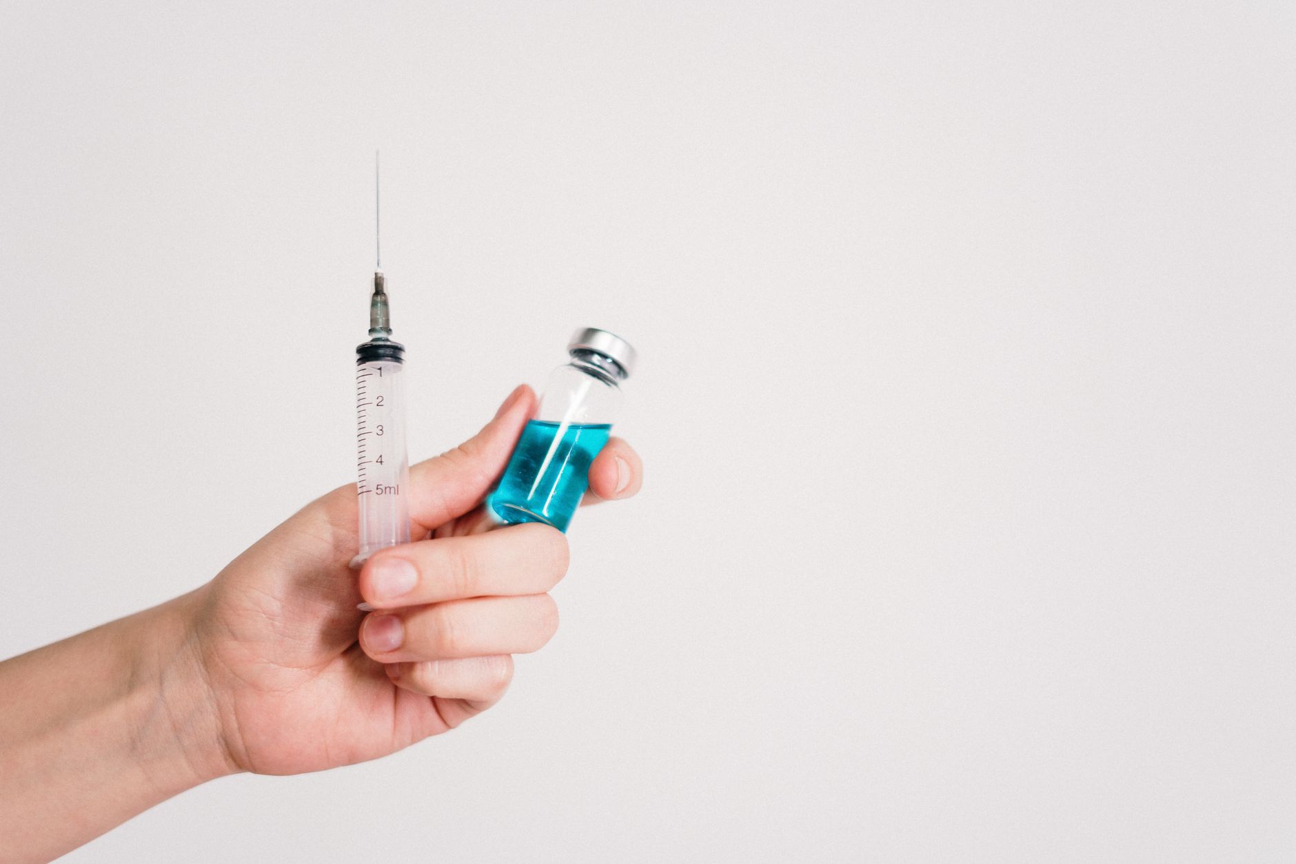 Close‑up of a prefilled RhoGAM syringe with a gentle hand holding it, soft natural light highlighting the clear liquid