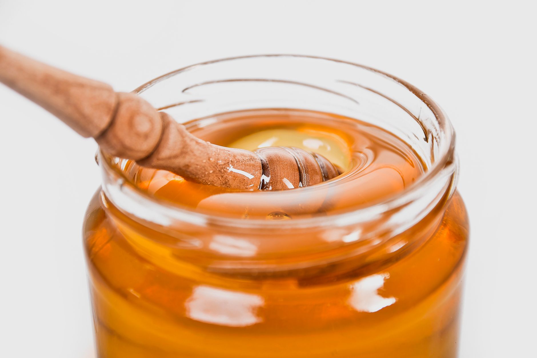 Close‑up of a small glass jar filled with homemade carrot‑apple puree, a wooden spoon, and a soft pastel napkin, illustrating a gentle, nutrient‑rich baby meal