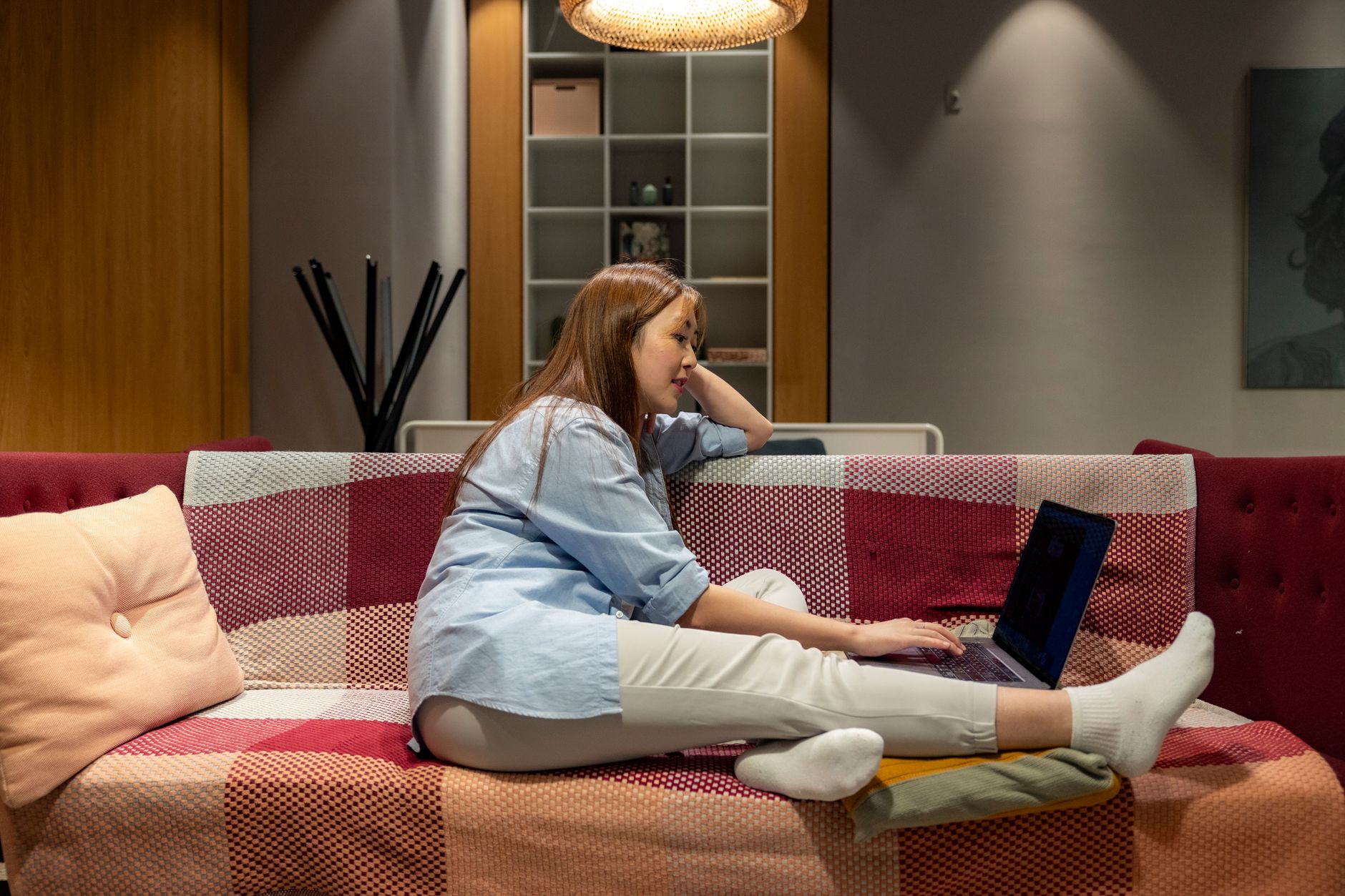 A mom working on her laptop in bed with her baby nearby, symbolizing flexible remote work