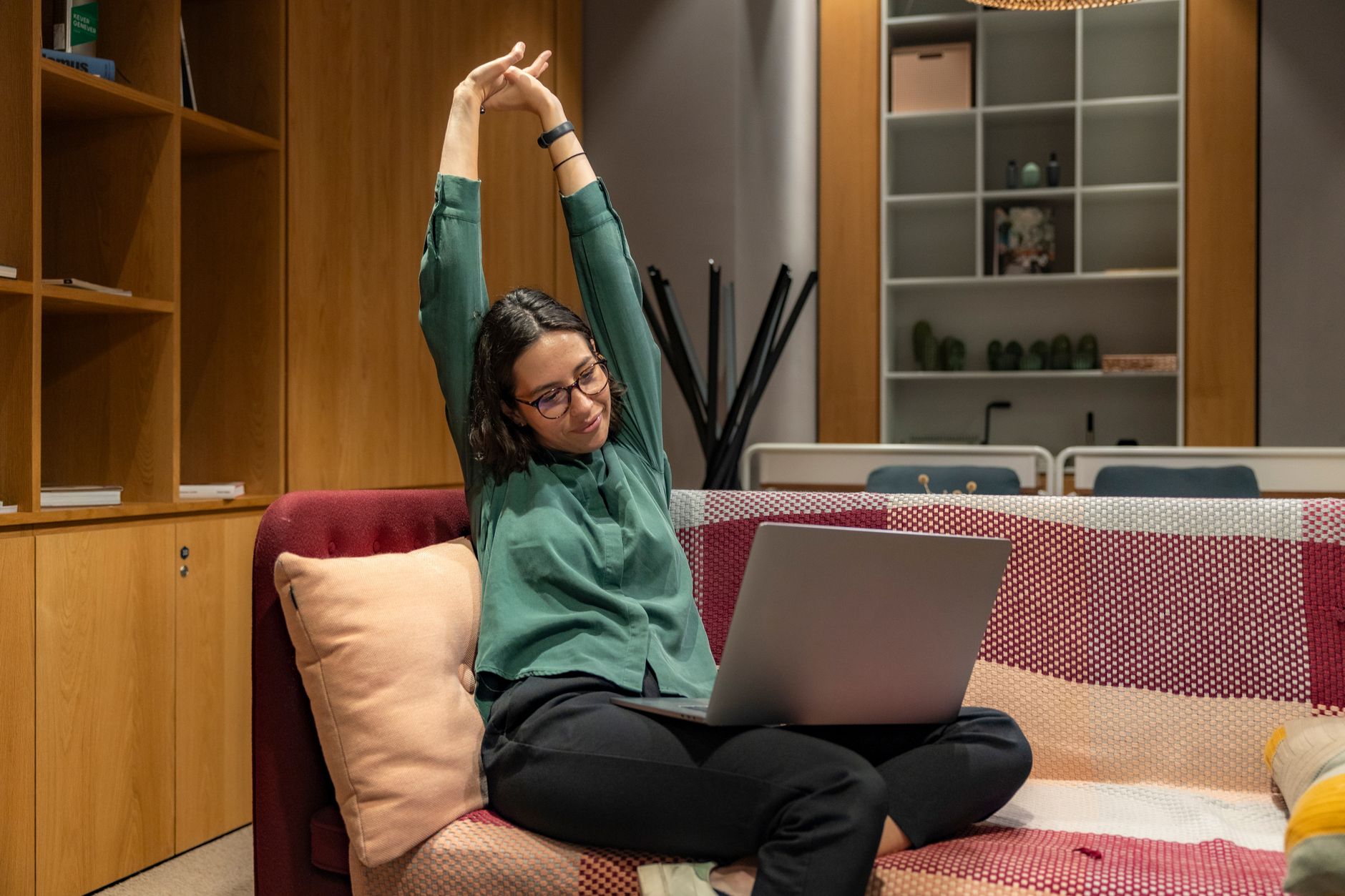 A woman in a home office setting with a laptop, baby monitor, and a to-do list, representing remote work flexibility