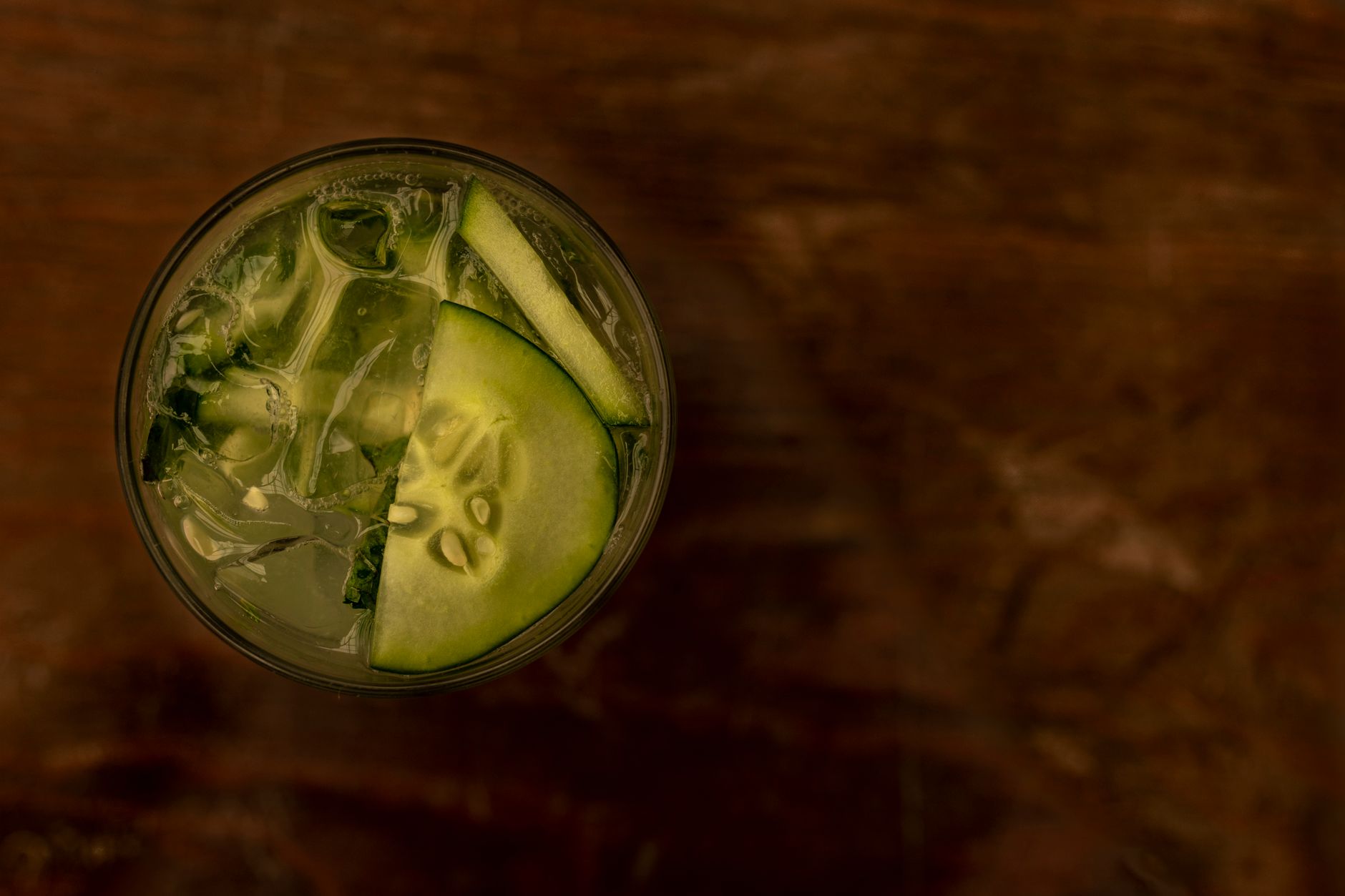 A glass of infused water with cucumber slices and a bowl of pumpkin seeds, illustrating healthy hydration and electrolyte sources for pregnant women