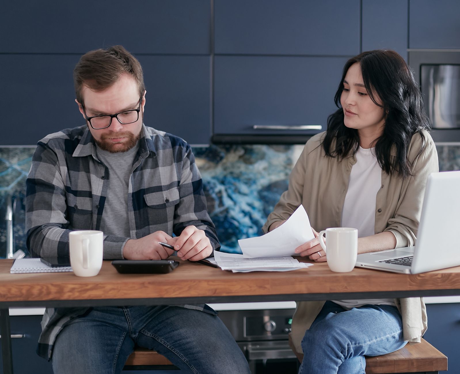 A smiling family of three sitting on a couch, with a piggy bank on the coffee table, symbolizing financial planning for foster-to-adopt families.