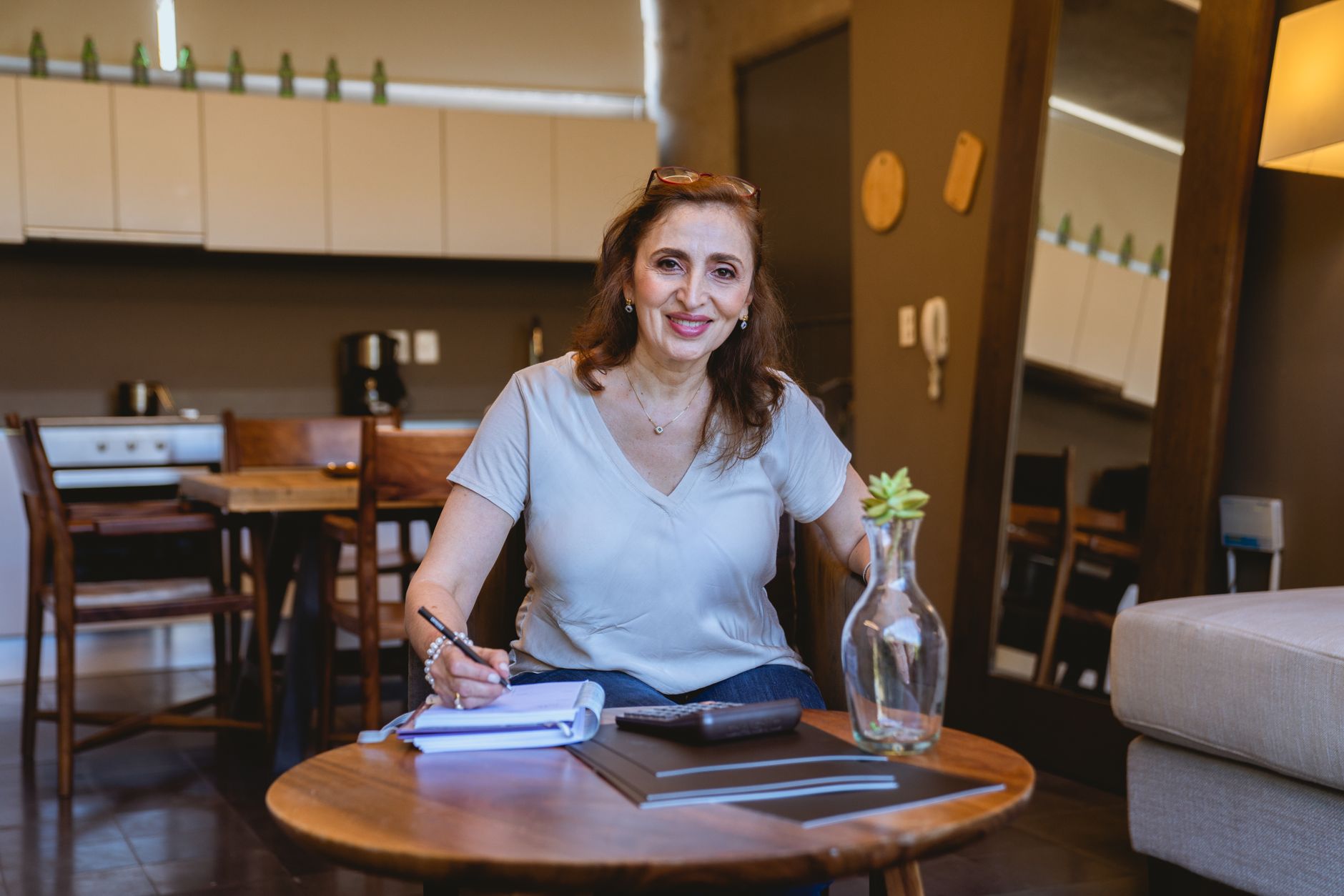 A smiling pregnant woman holding a glucose meter and a notebook, planning her diet and monitoring her blood sugar levels