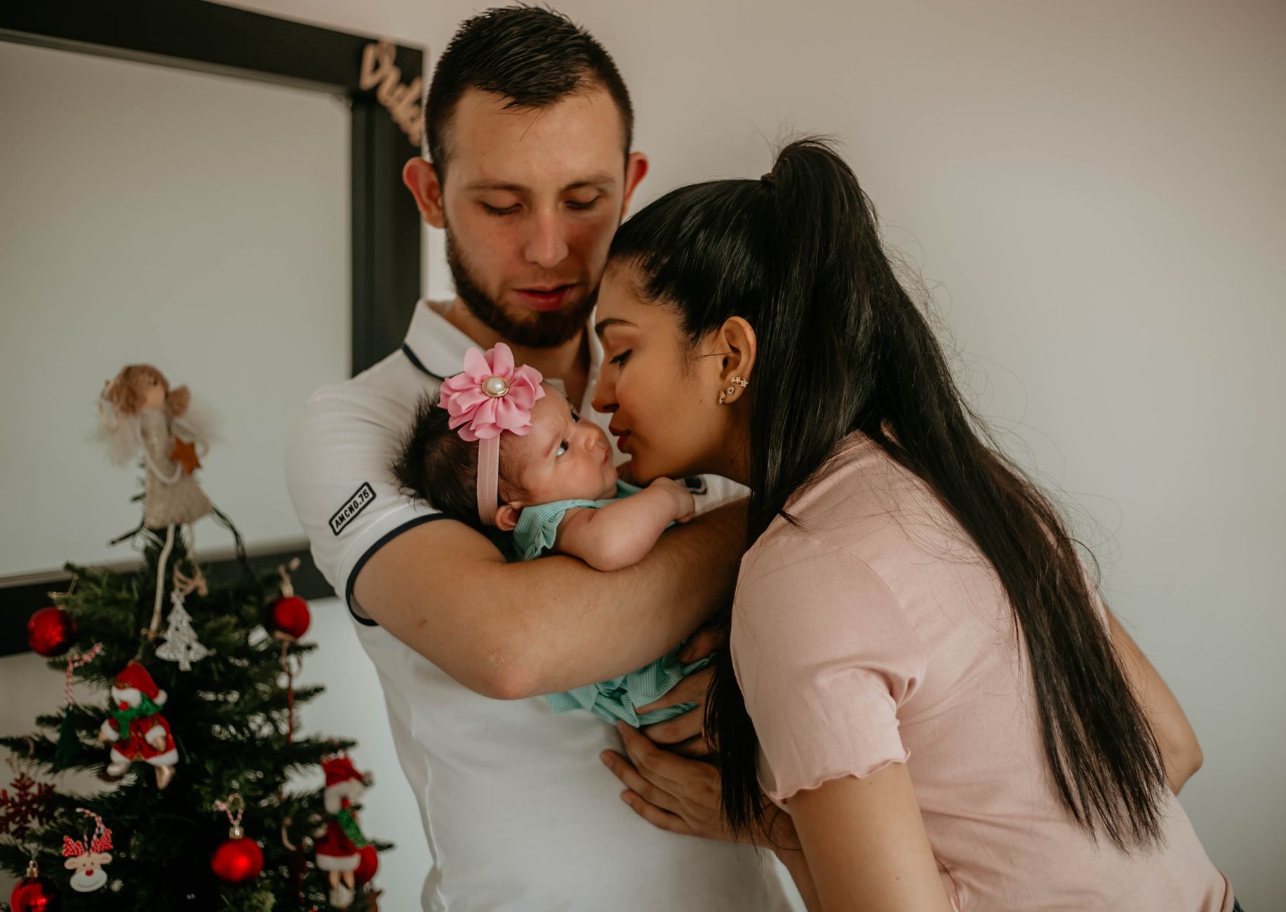 A joyful couple holding their newborn baby, smiling at the camera after a successful surrogacy