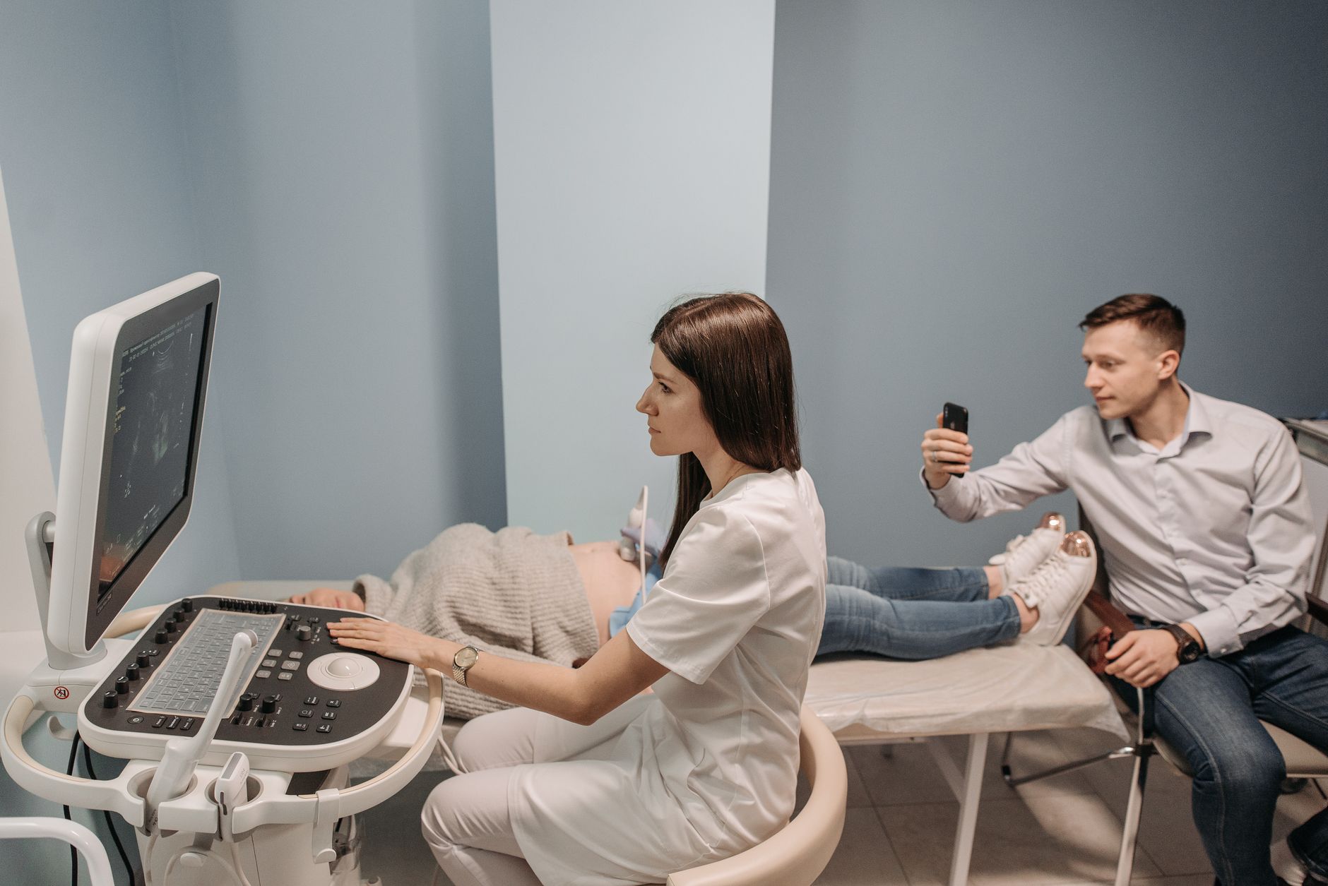 A surrogate and intended parents sitting in a medical consultation, reviewing ultrasound images