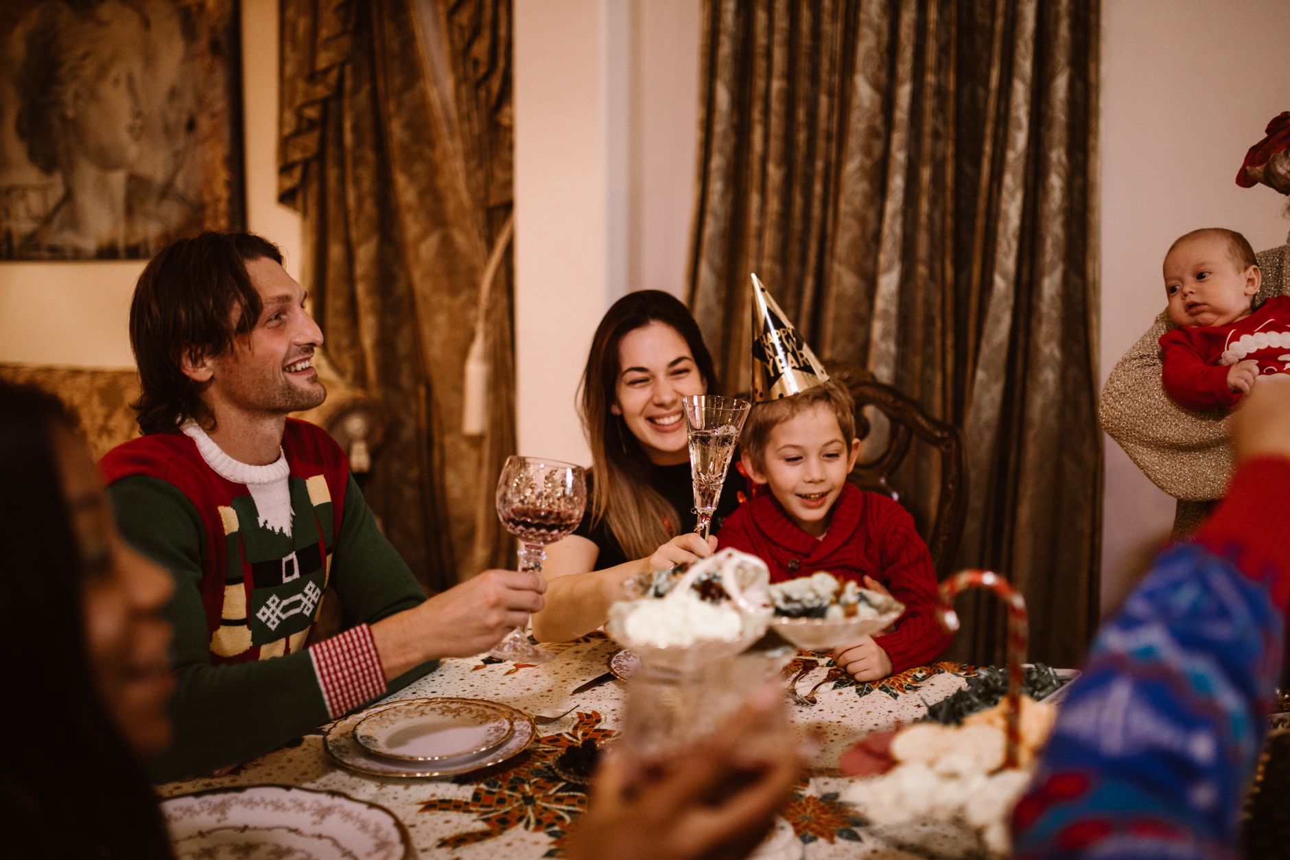 Family celebrating individual strengths at dinner, each child holding up a handmade card with their unique accomplishment.