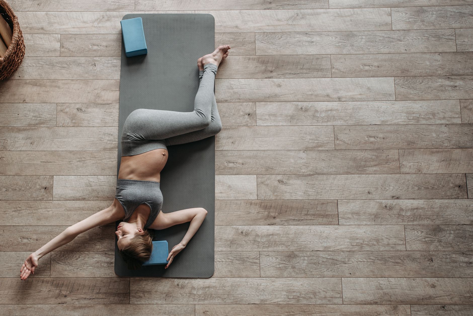 A prenatal yoga mat rolled out next to a glass of water and a small bowl of almonds, bright morning light