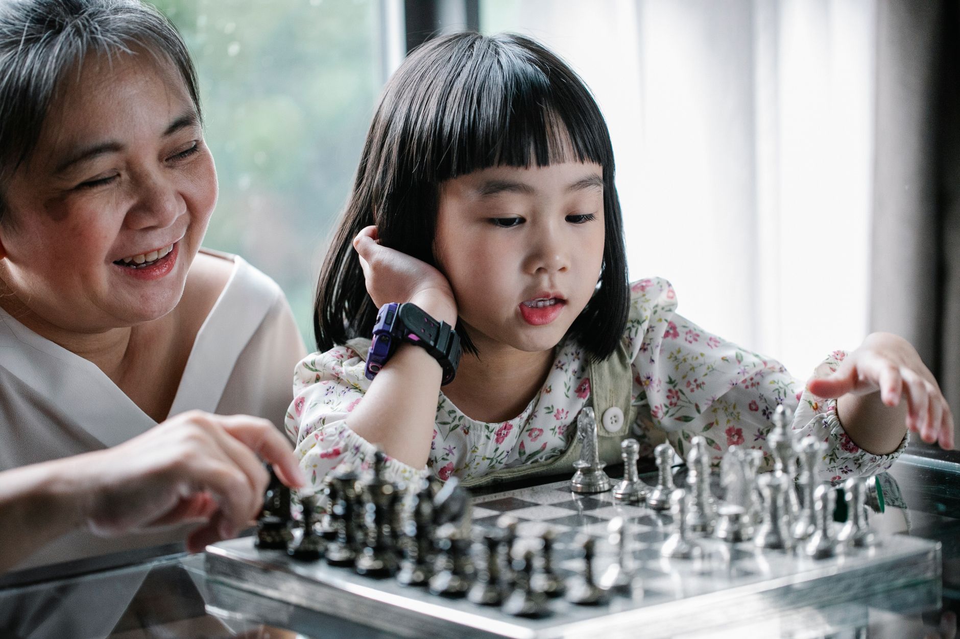 A grandparent and toddler playing with wooden blocks on a coffee table, with a phone nearby but unused