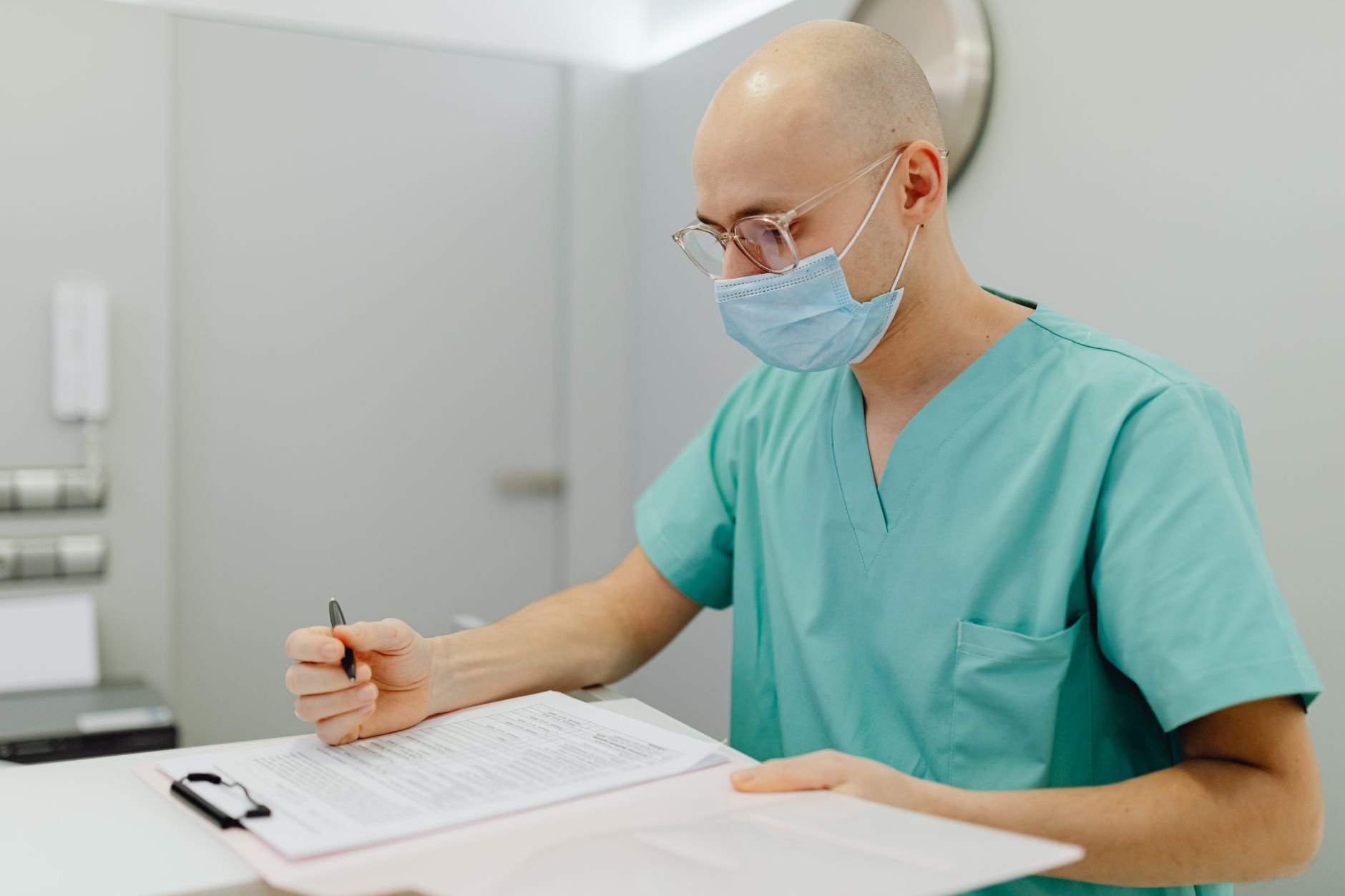 A nurse writing in a mother’s labor chart, with a tablet displaying the GBS antibiotic schedule beside a stethoscope and a cup of water