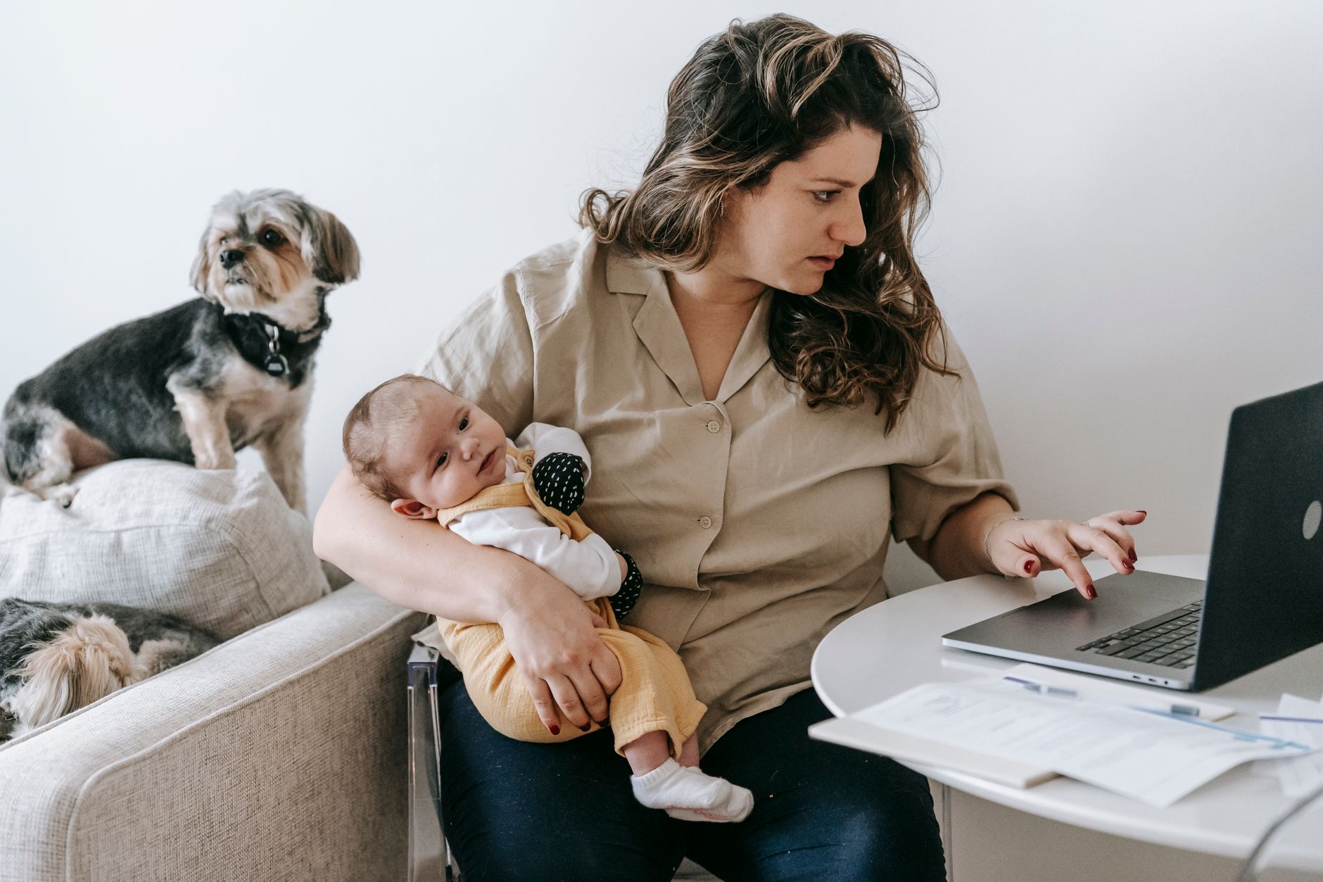 Young mother balancing laptop work and baby in a home office