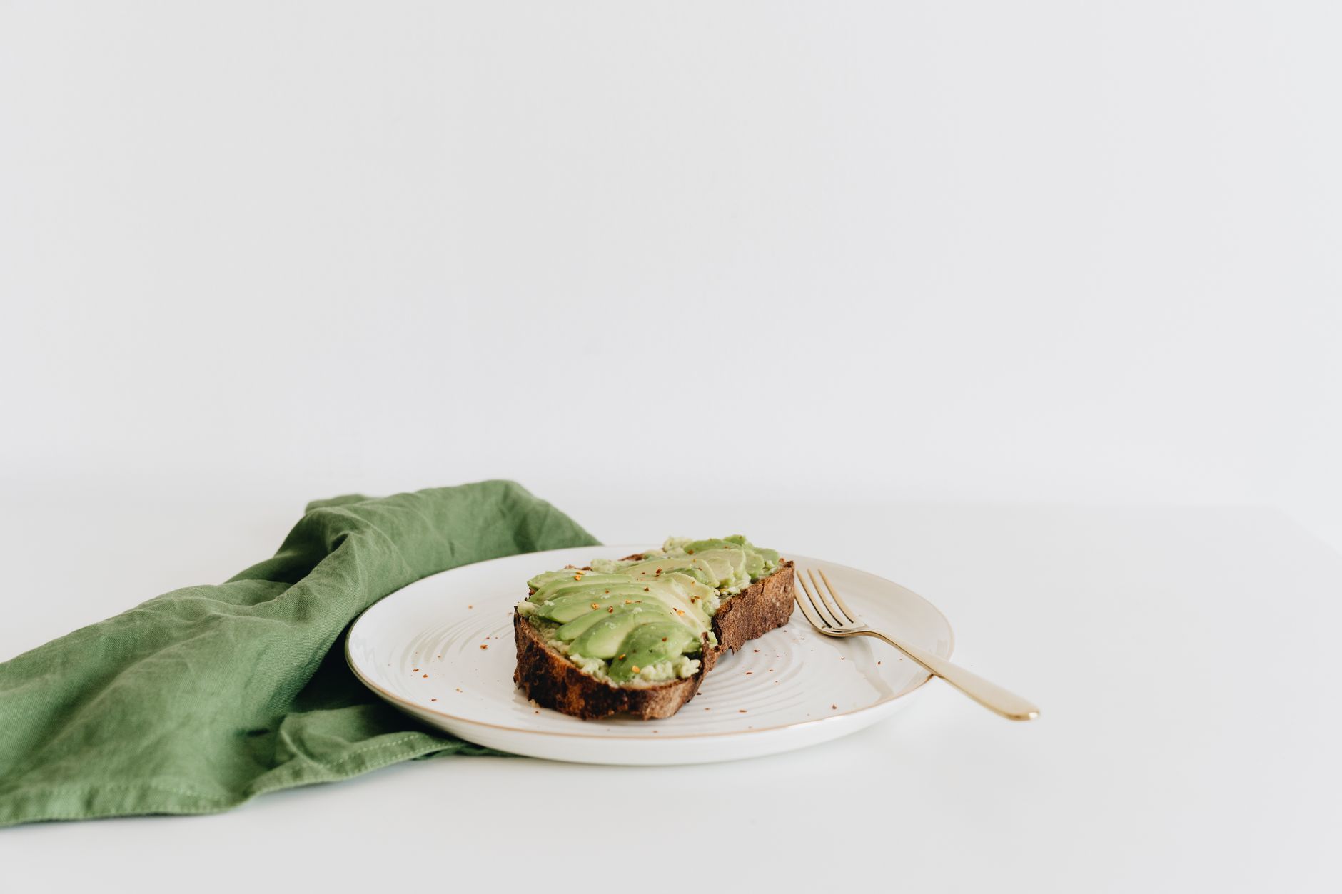 A pregnant woman enjoying a healthy snack of sliced avocado on whole-grain toast in a bright kitchen