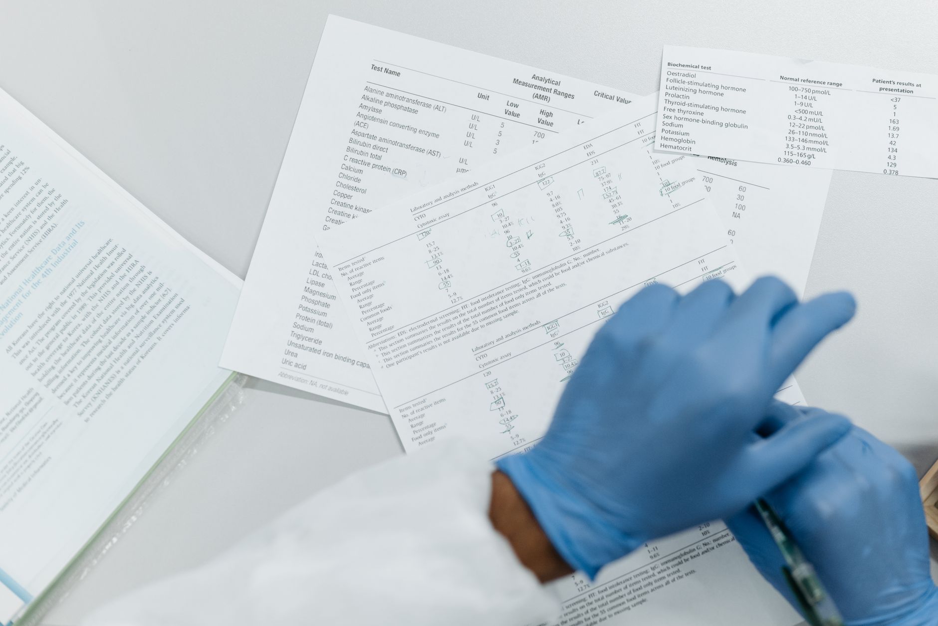 Pregnant woman's hands holding a printed lab report, with highlighted values for LDH, AST, and platelets, set on a soft linen table