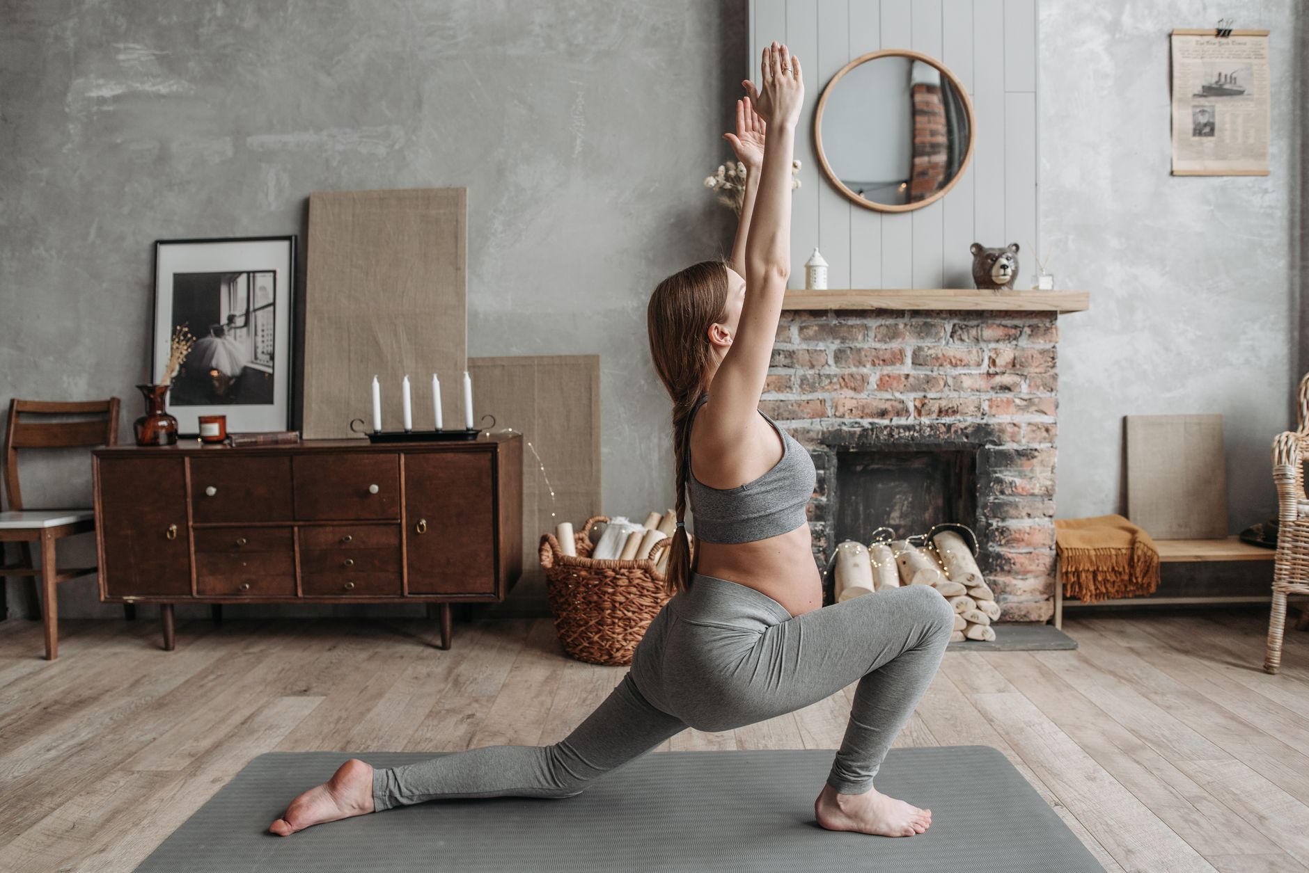 Pregnant woman doing a gentle prenatal yoga stretch on a yoga mat in a sunlit room
