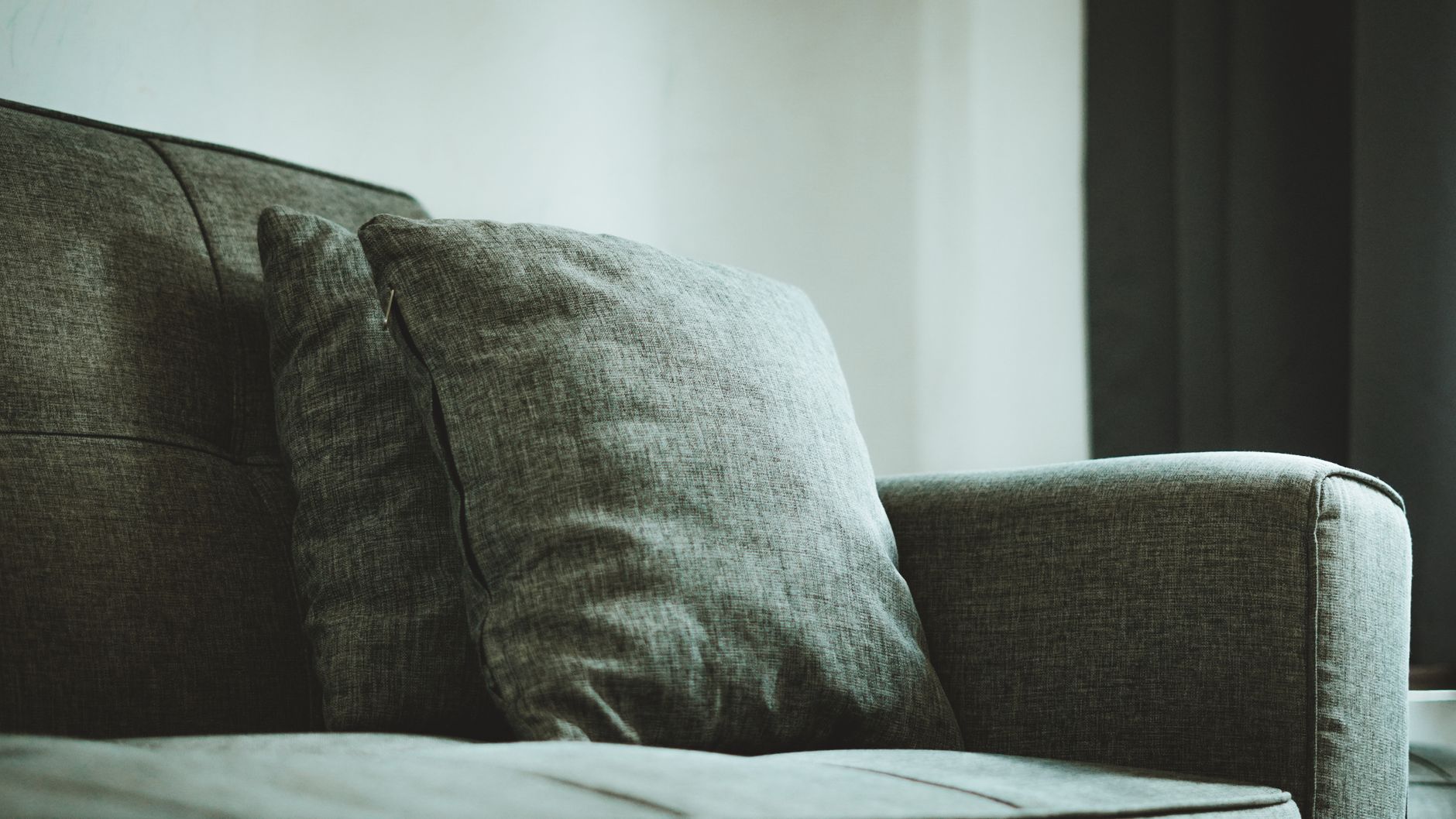 Pregnant woman gently massaging her abdomen while sitting on a cozy couch, soft natural light, a steaming mug of herbal tea nearby