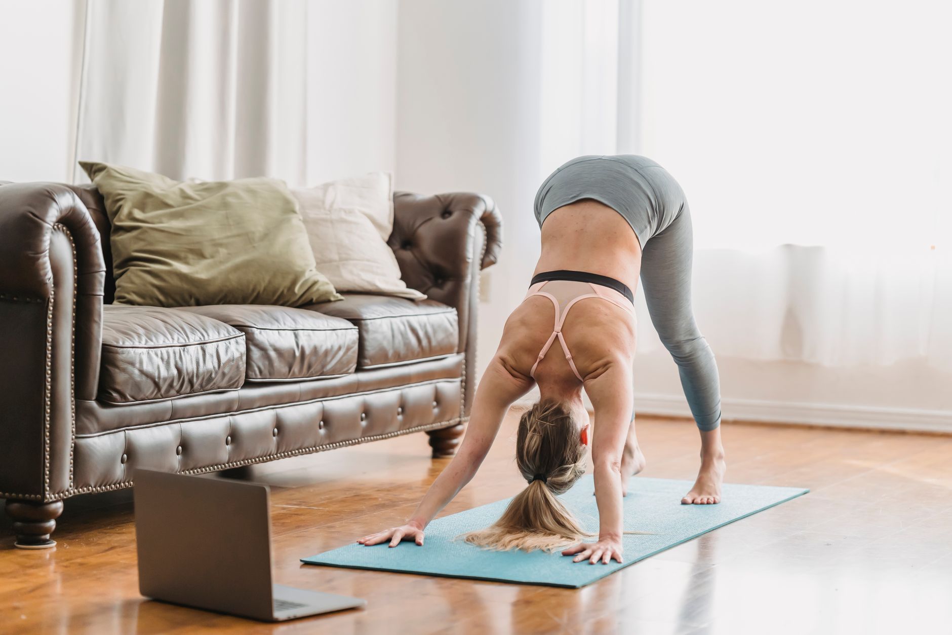 A woman in activewear performs the bird-dog exercise on a yoga mat, extending her left arm and right leg while maintaining a flat back.