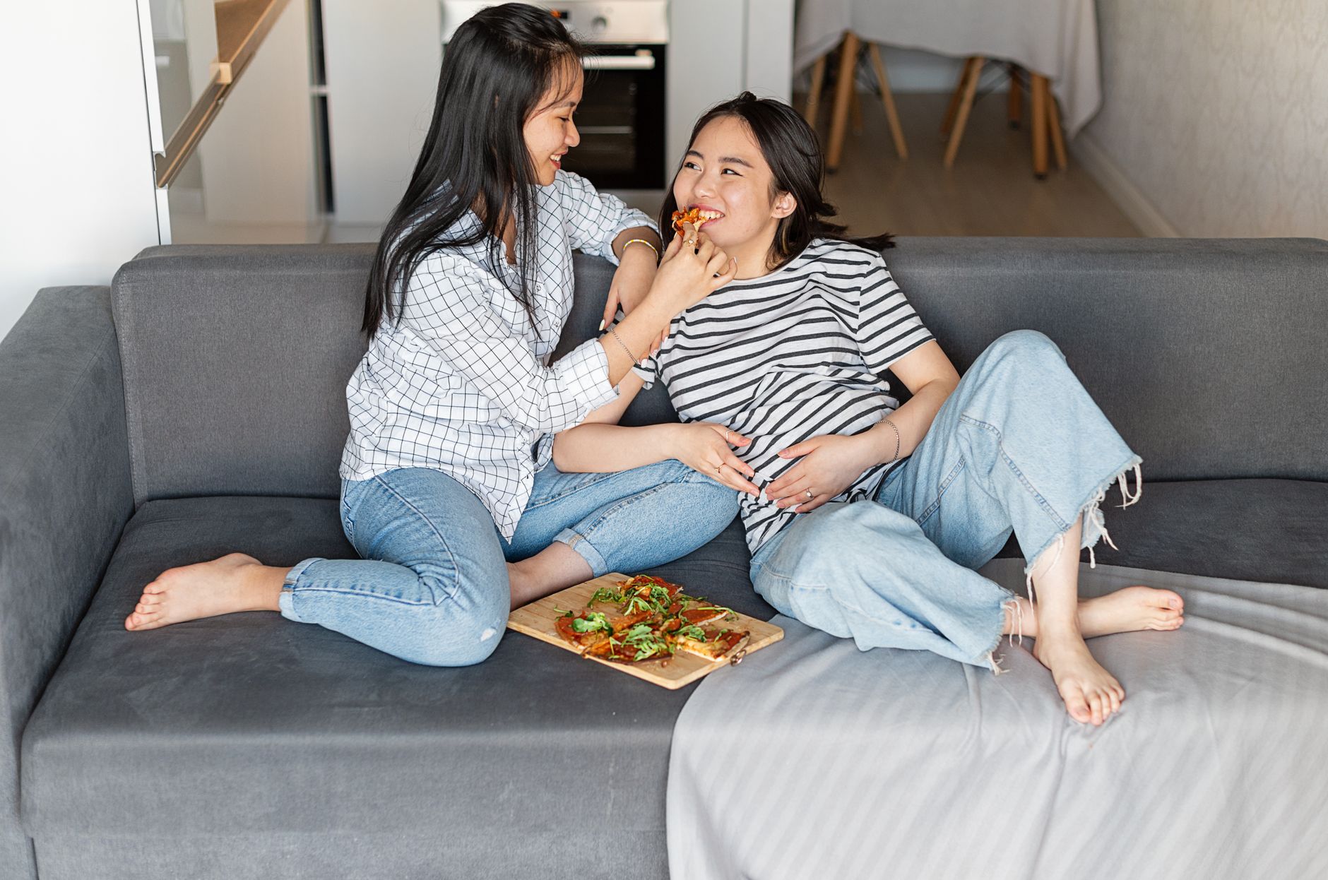 Pregnant couple sitting on a hospital couch, sharing a snack, soft lighting, warm tones, relaxed atmosphere