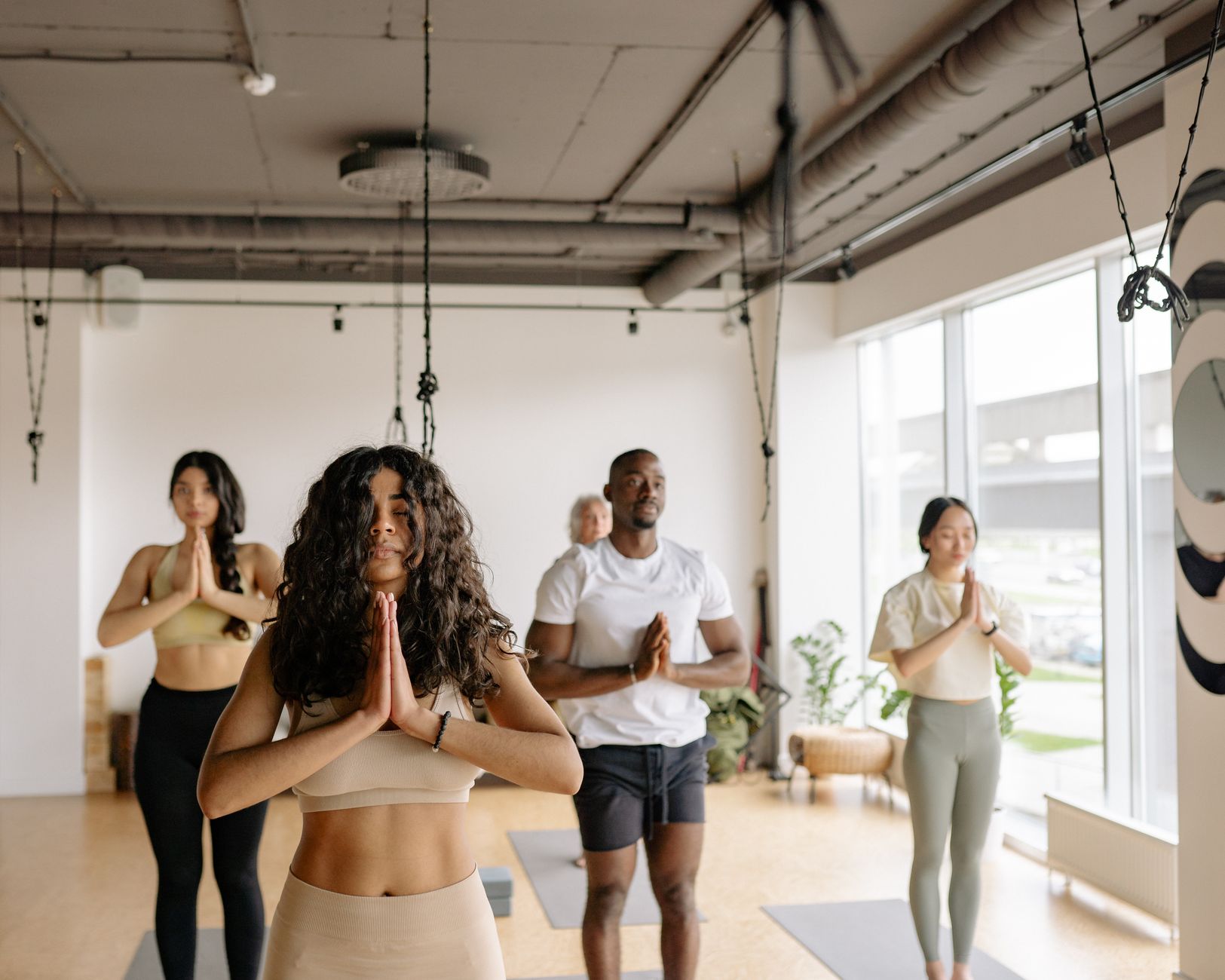 A peaceful yoga studio with a small group of moms practicing gentle hot yoga, focusing on breathwork and pelvic floor-friendly poses.