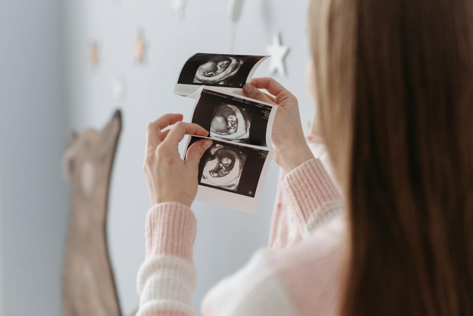 A happy pregnant woman looking at an ultrasound image, with a gentle smile