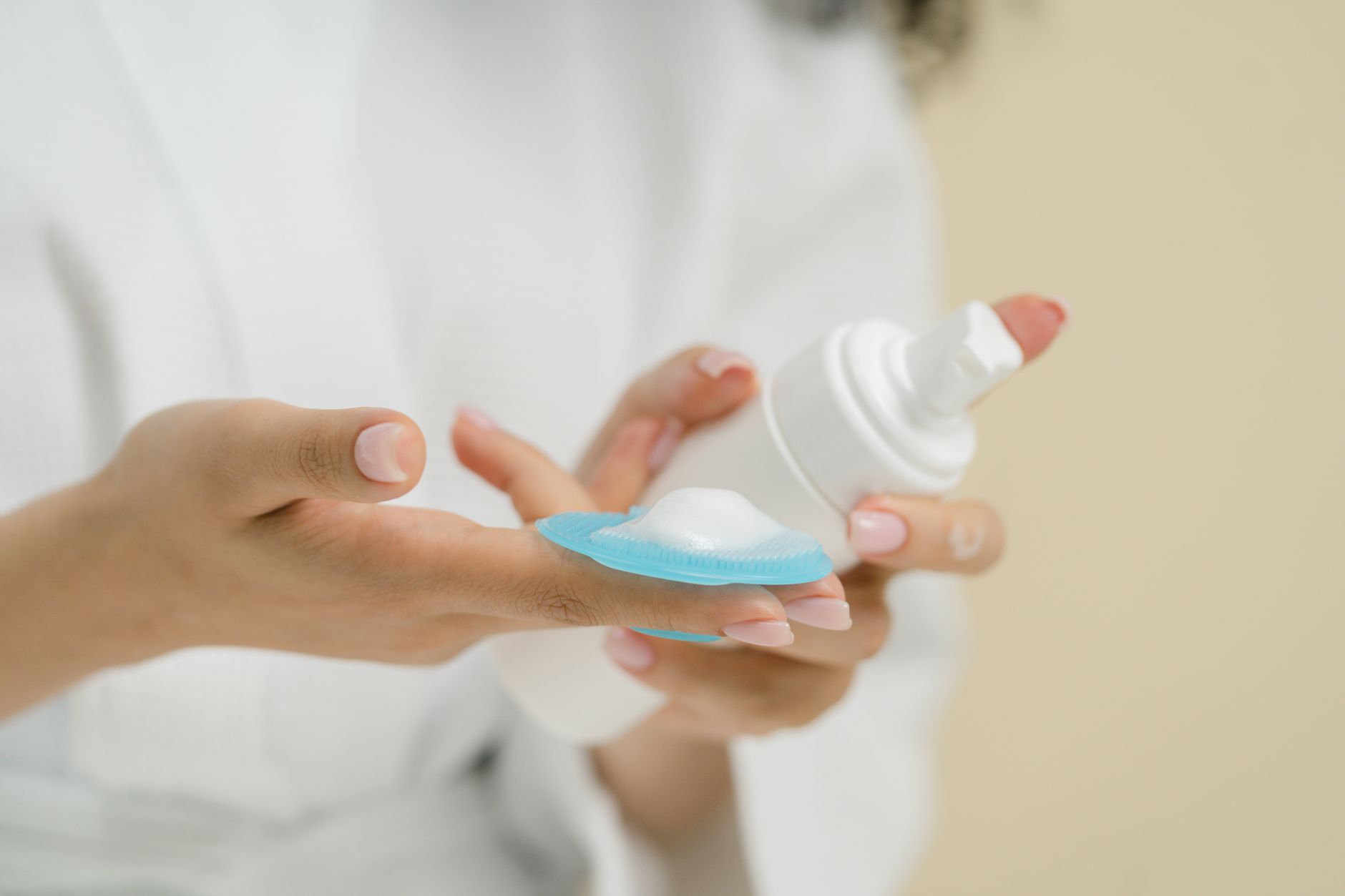 A woman's hand gently holding a peri bottle over her perineal area, soft focus on the water stream, in a clean bathroom setting