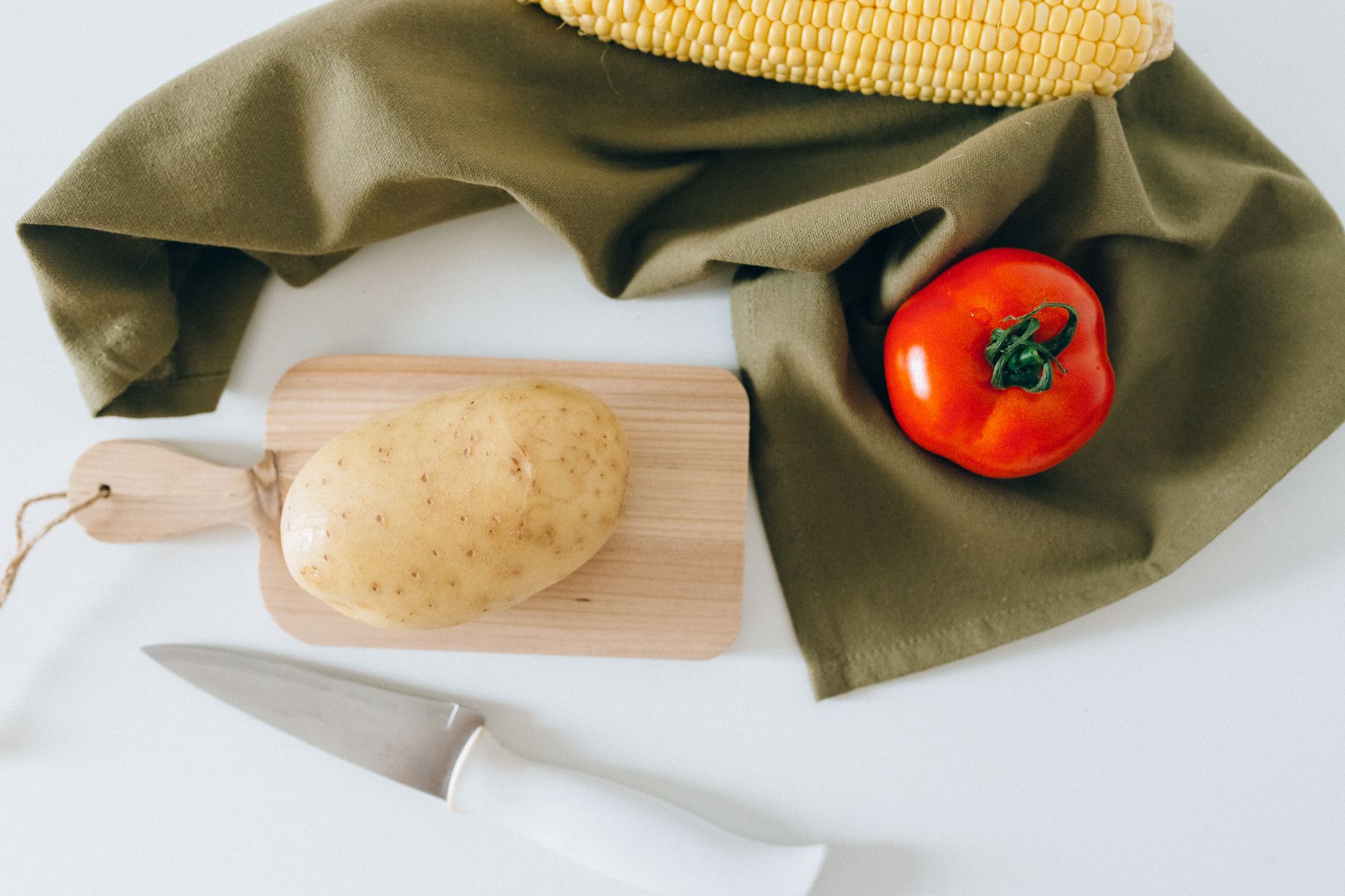A wooden board with an ear of corn, a banana, and an eggplant to show baby size at 24 weeks
