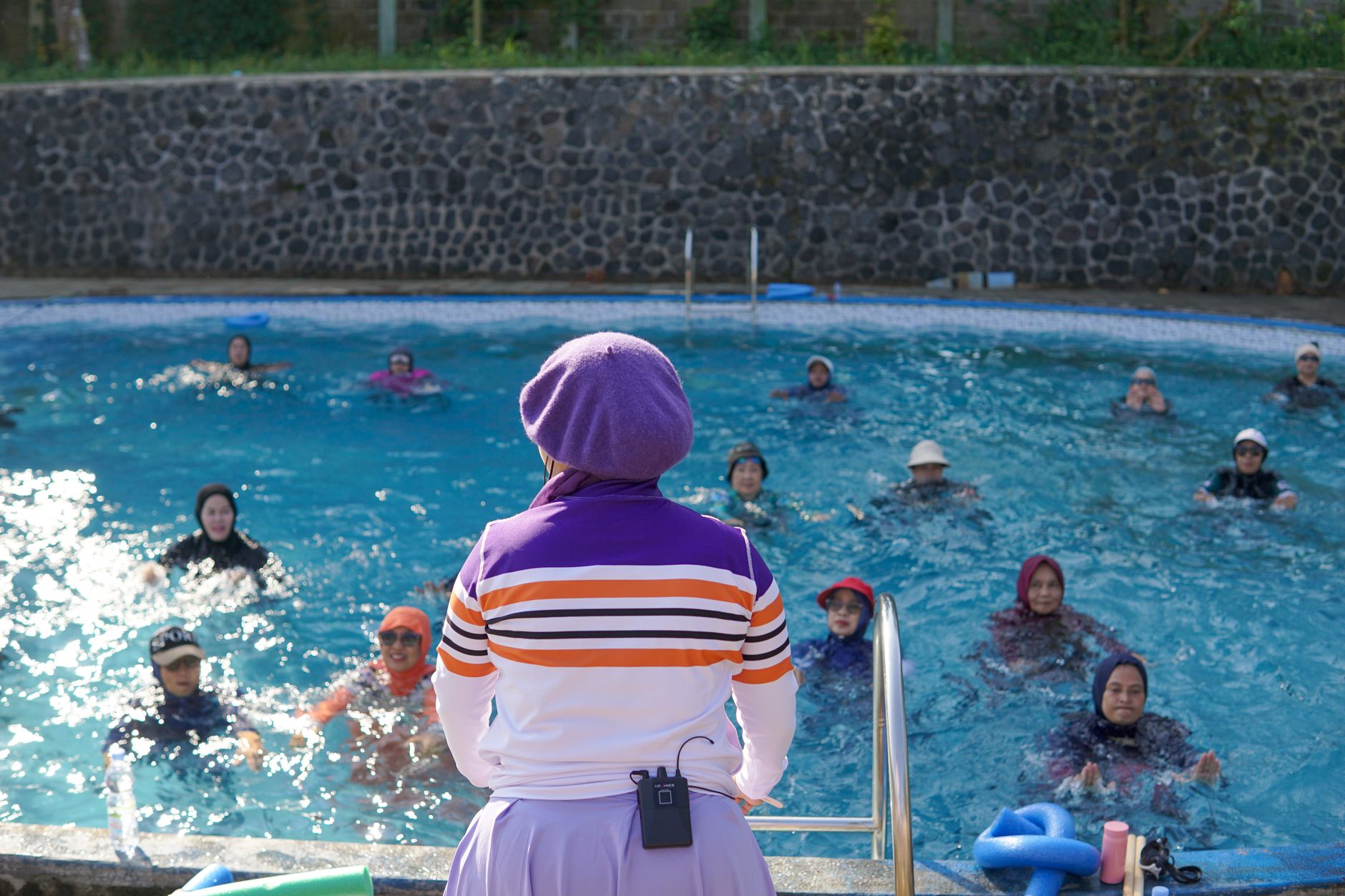 A pregnant woman in a pool, smiling as she participates in a prenatal water aerobics class