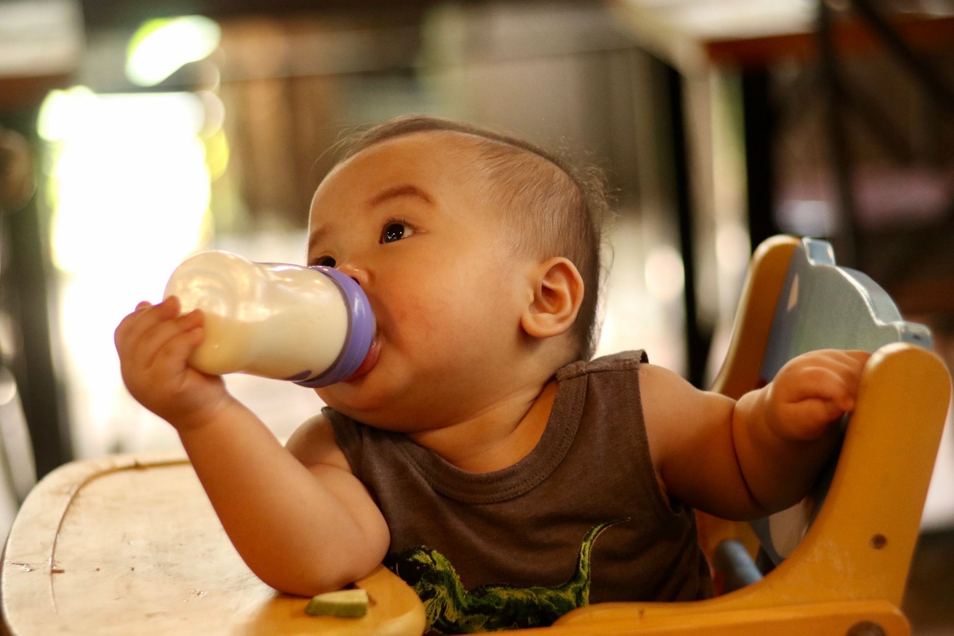 Toddler eating solid foods with breastmilk bottle