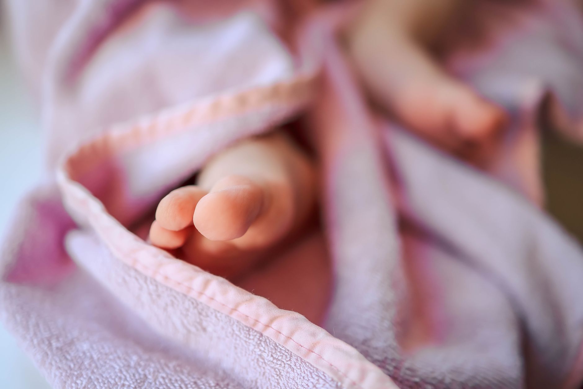 Close‑up of a newborn baby sleeping on a soft blanket, highlighting its size and weight