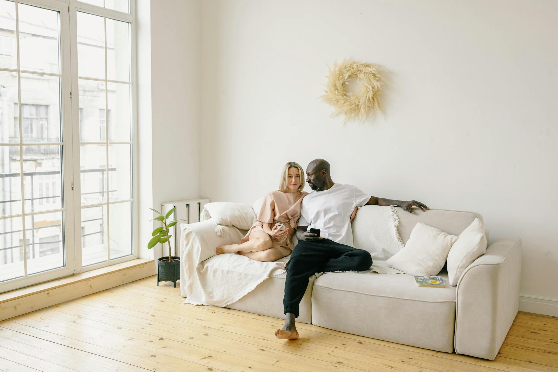 A diverse couple holding a newborn, sitting on a cozy sofa with soft lighting, showing inclusion and warmth