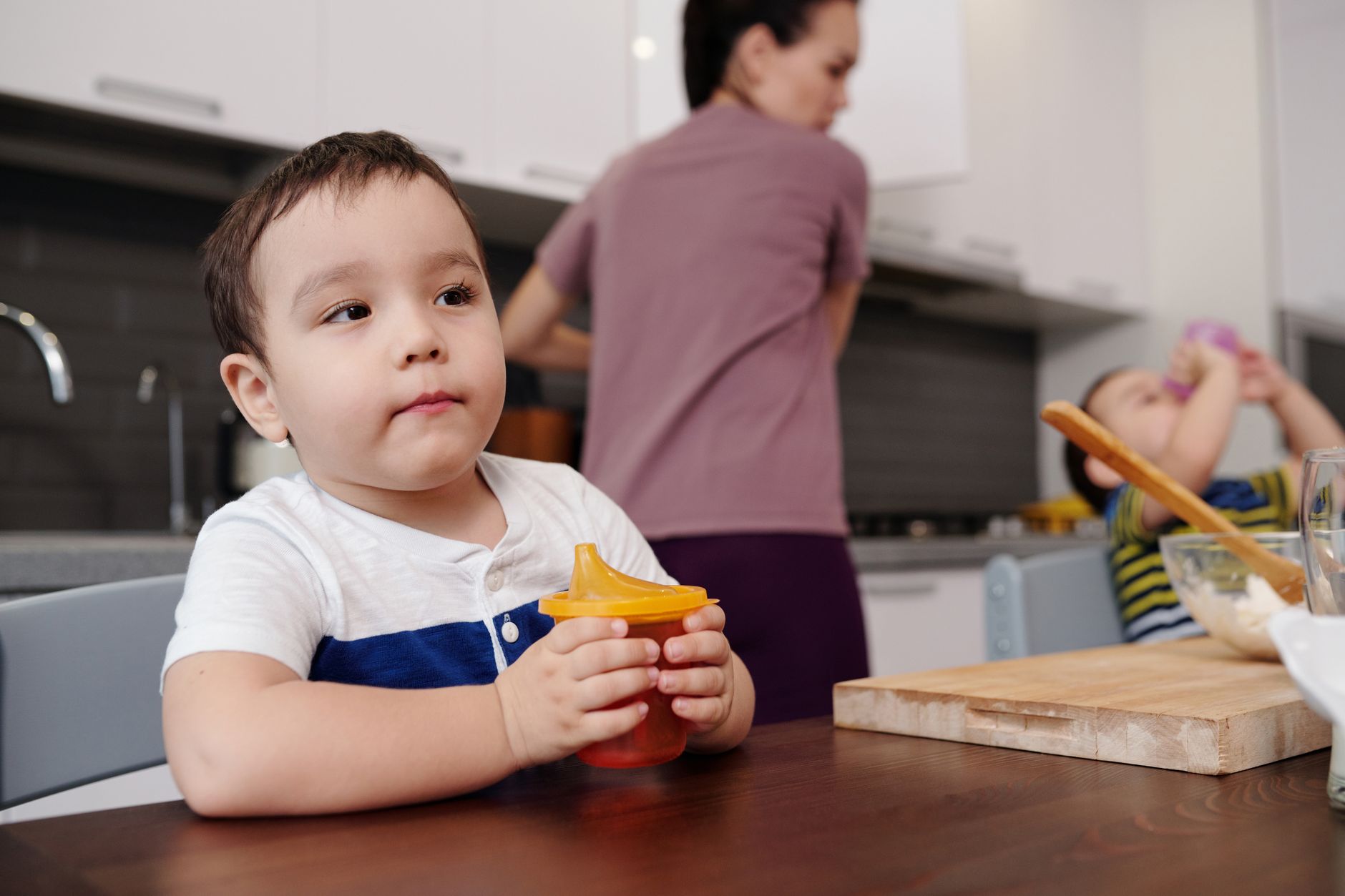 Toddler reaching for a sippy cup of milk
