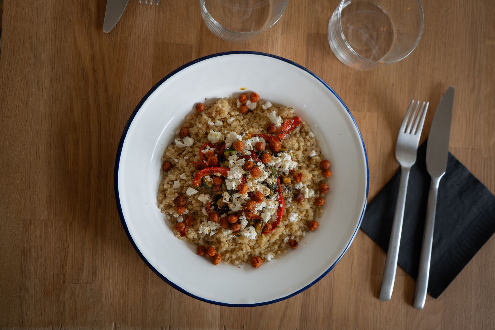Pregnant woman in a sunny kitchen, preparing a quinoa and black bean bowl with fresh vegetables, showing a balanced high‑protein meal