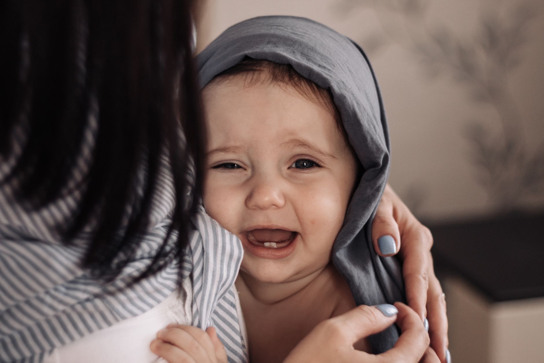 A worried parent holding a crying baby, symbolizing the distress and anxiety parents feel when their infant is uncomfortable.