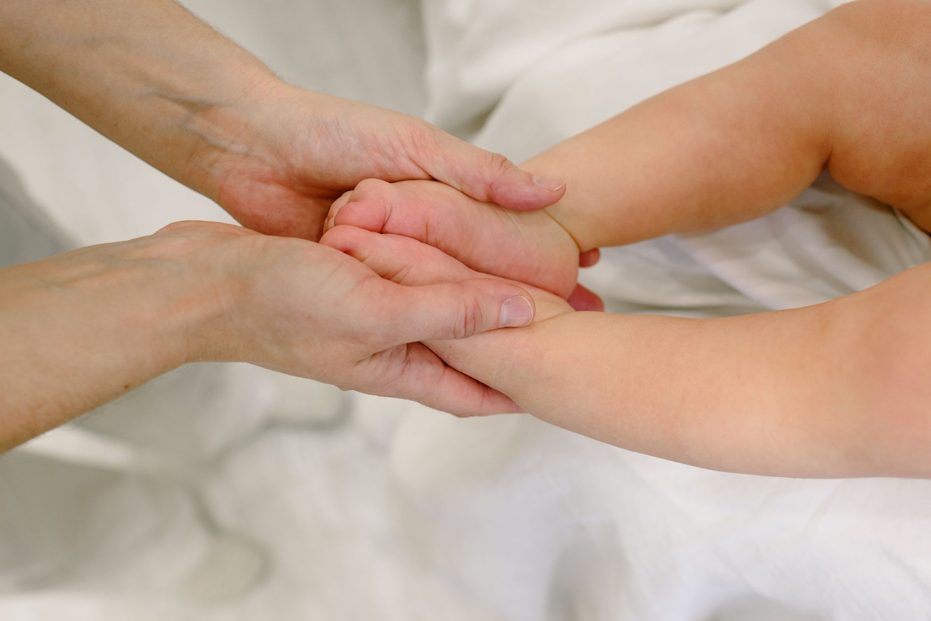 A parent gently rubbing a baby's tummy, illustrating infant massage for gas relief.