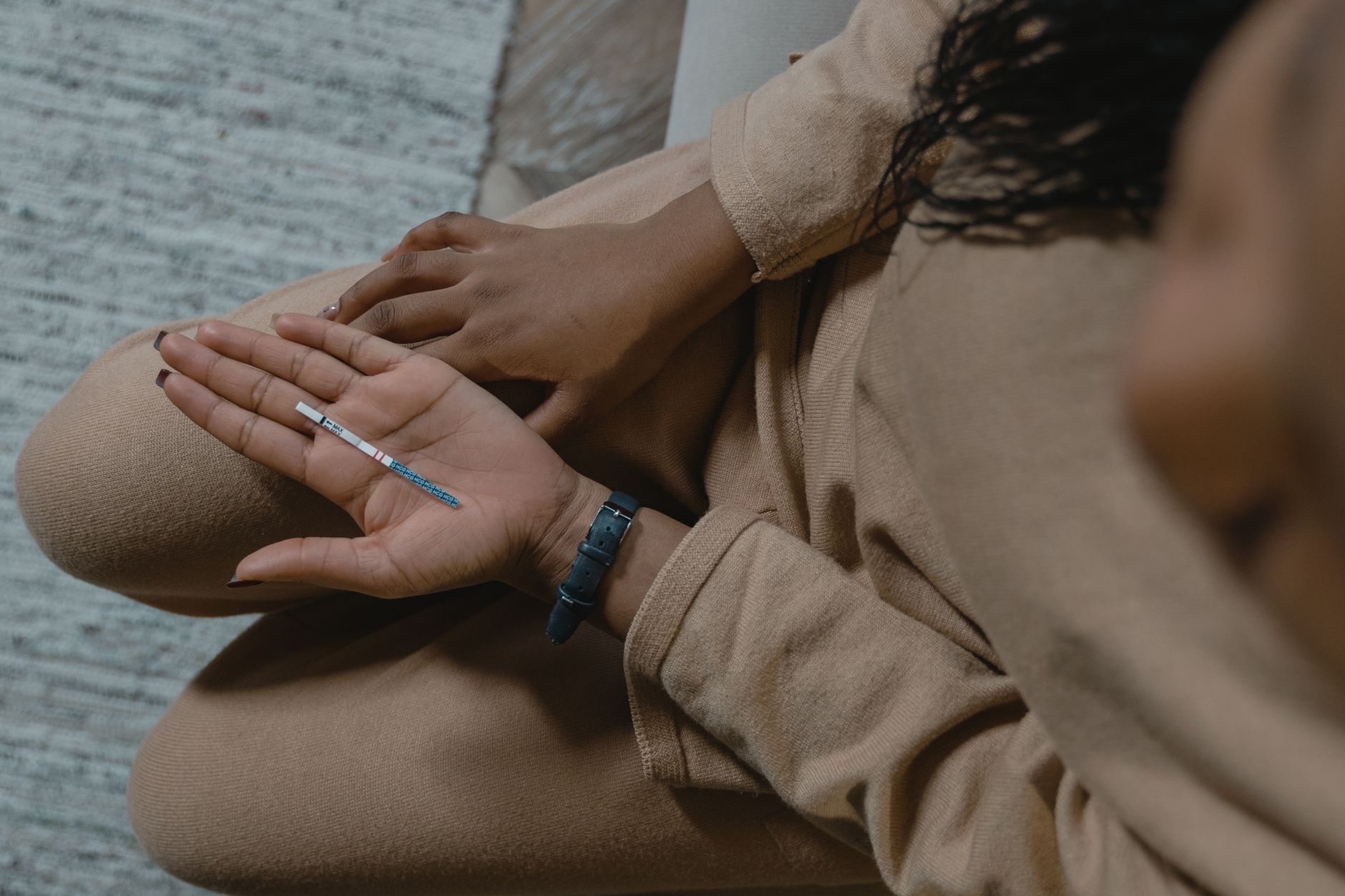 A woman holding a pregnancy test and looking at it with a hopeful expression, soft natural light