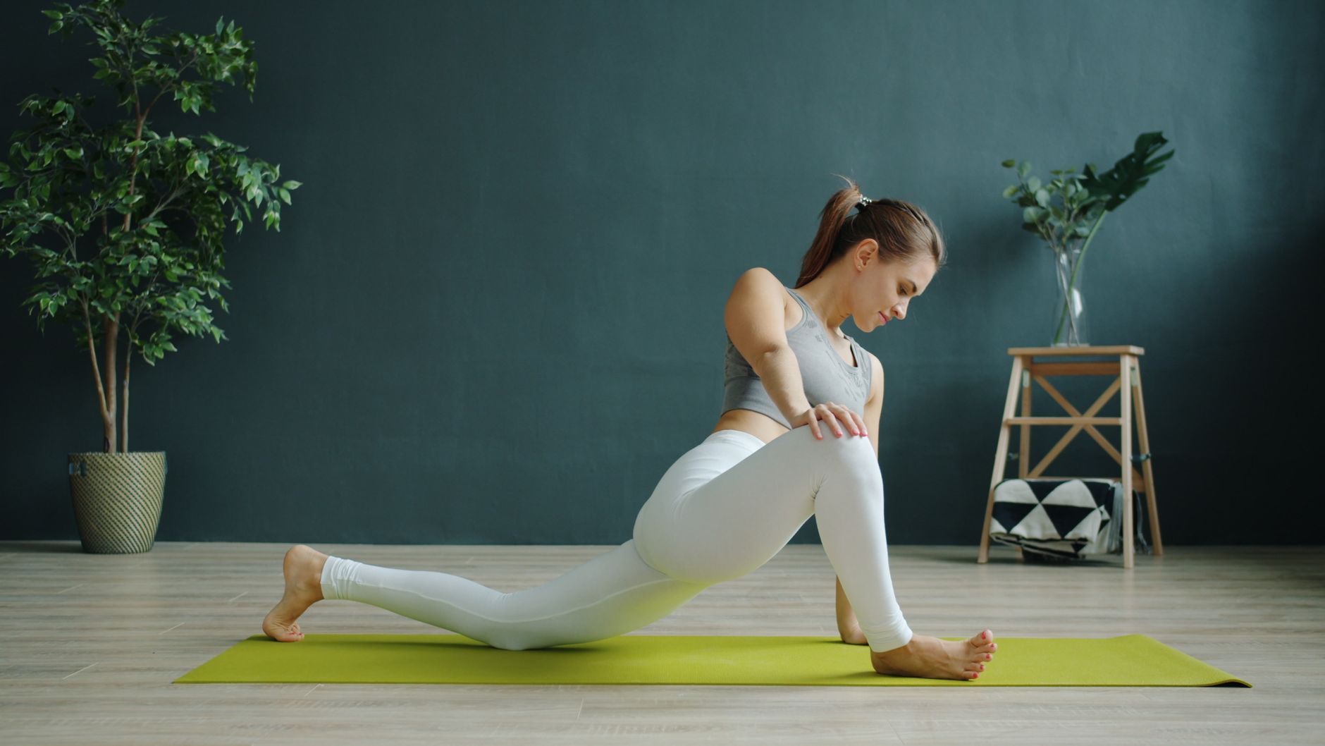 A woman doing gentle yoga stretches in a sunlit room, emphasizing flexibility and calm