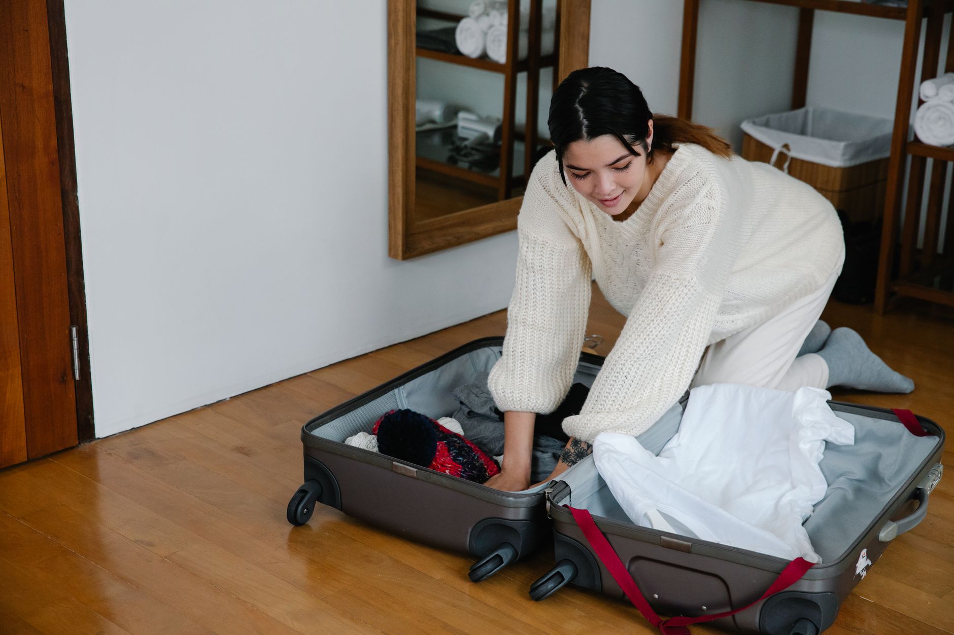 A pregnant woman packing a hospital bag, with baby clothes and toiletries visible, cozy bedroom setting