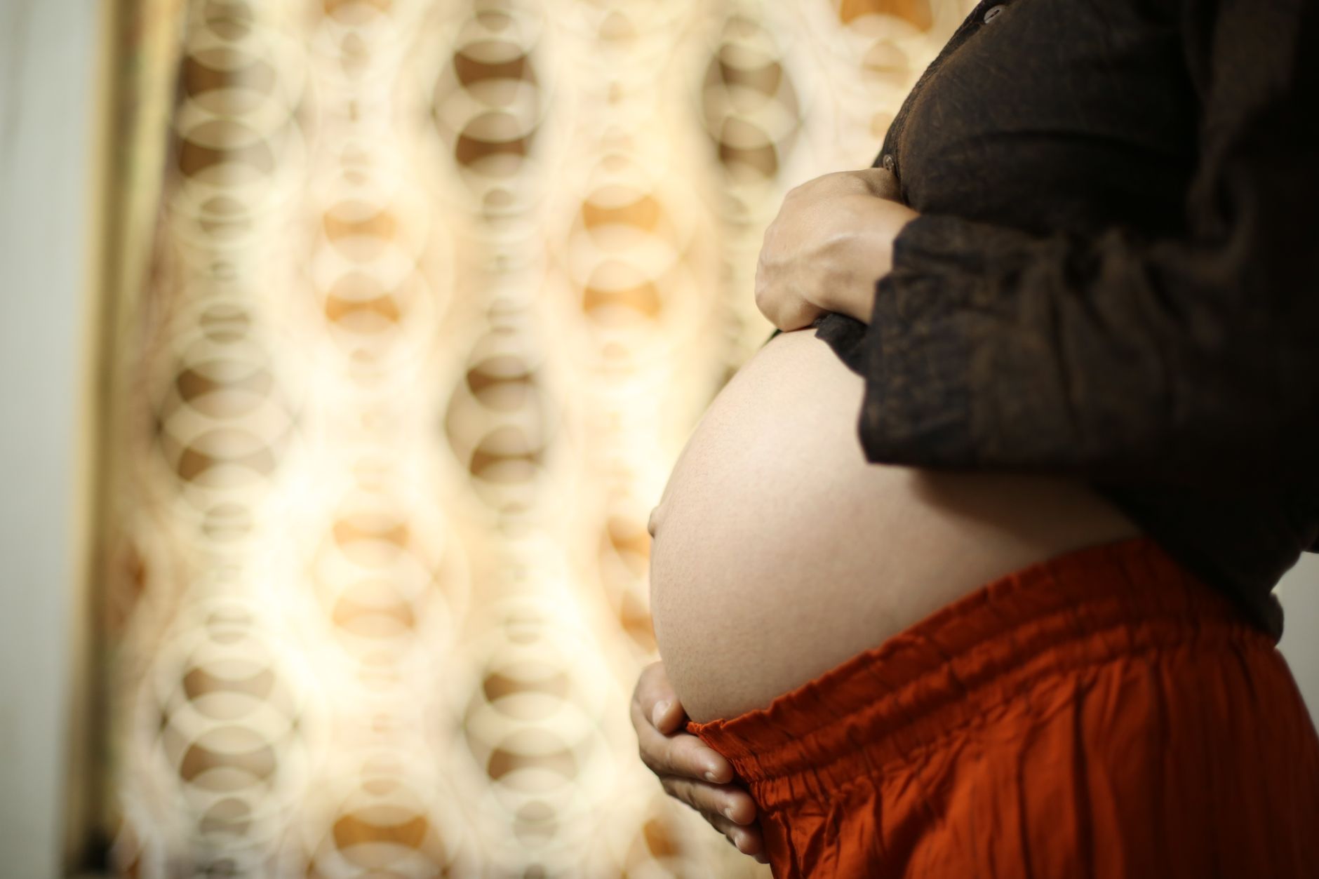 A close-up shot of a pregnant woman's belly with a slight ripple, indicating fetal movement.
