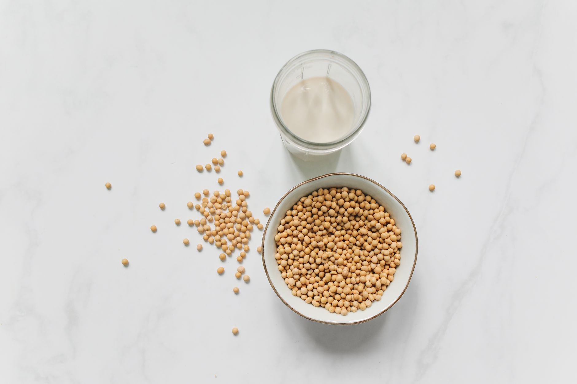 Three bottles of infant formula—cow's milk, soy, and hypoallergenic—arranged on a light wooden surface with a measuring scoop beside them