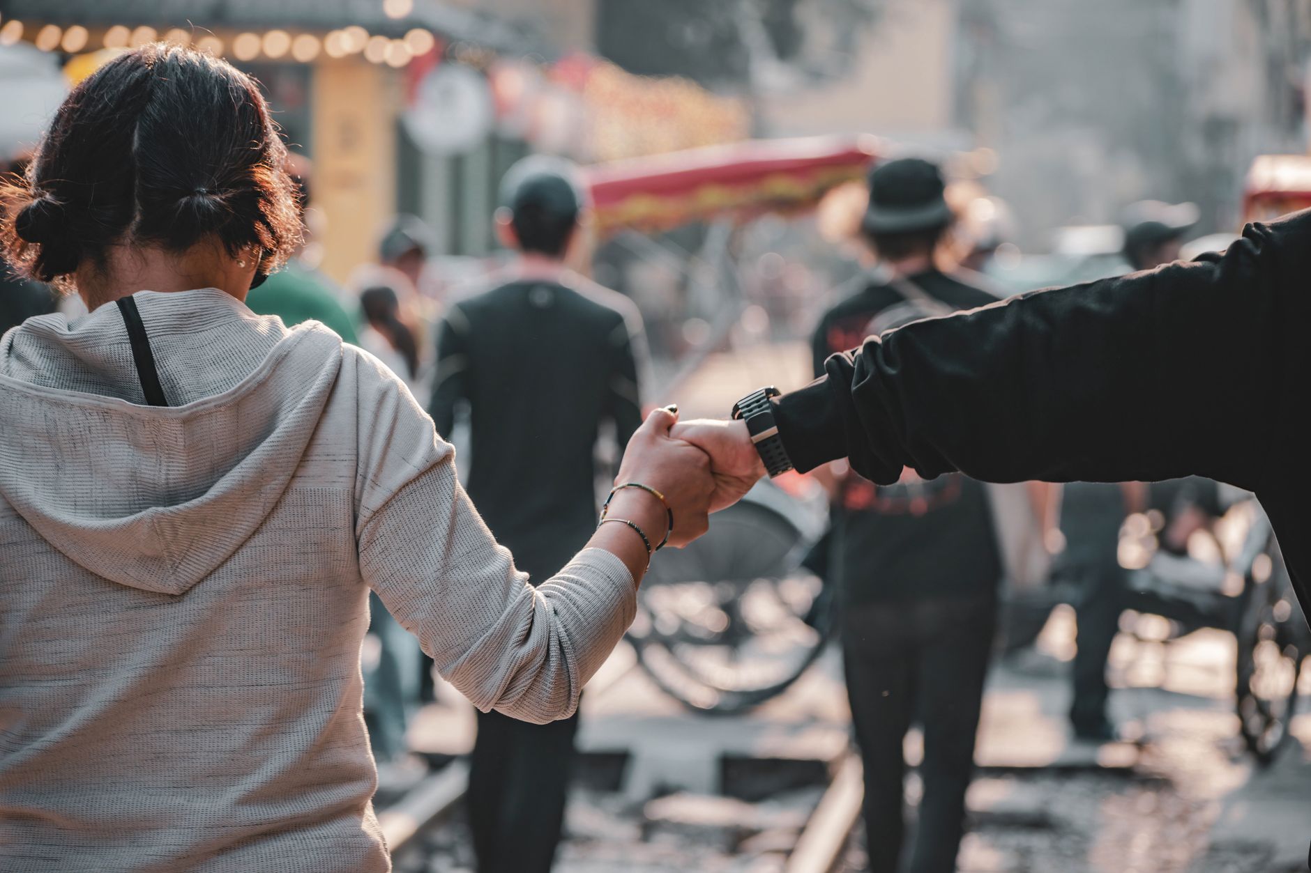 A parent holding their child's hand firmly while walking through a busy street, focusing on safety amidst a crowd