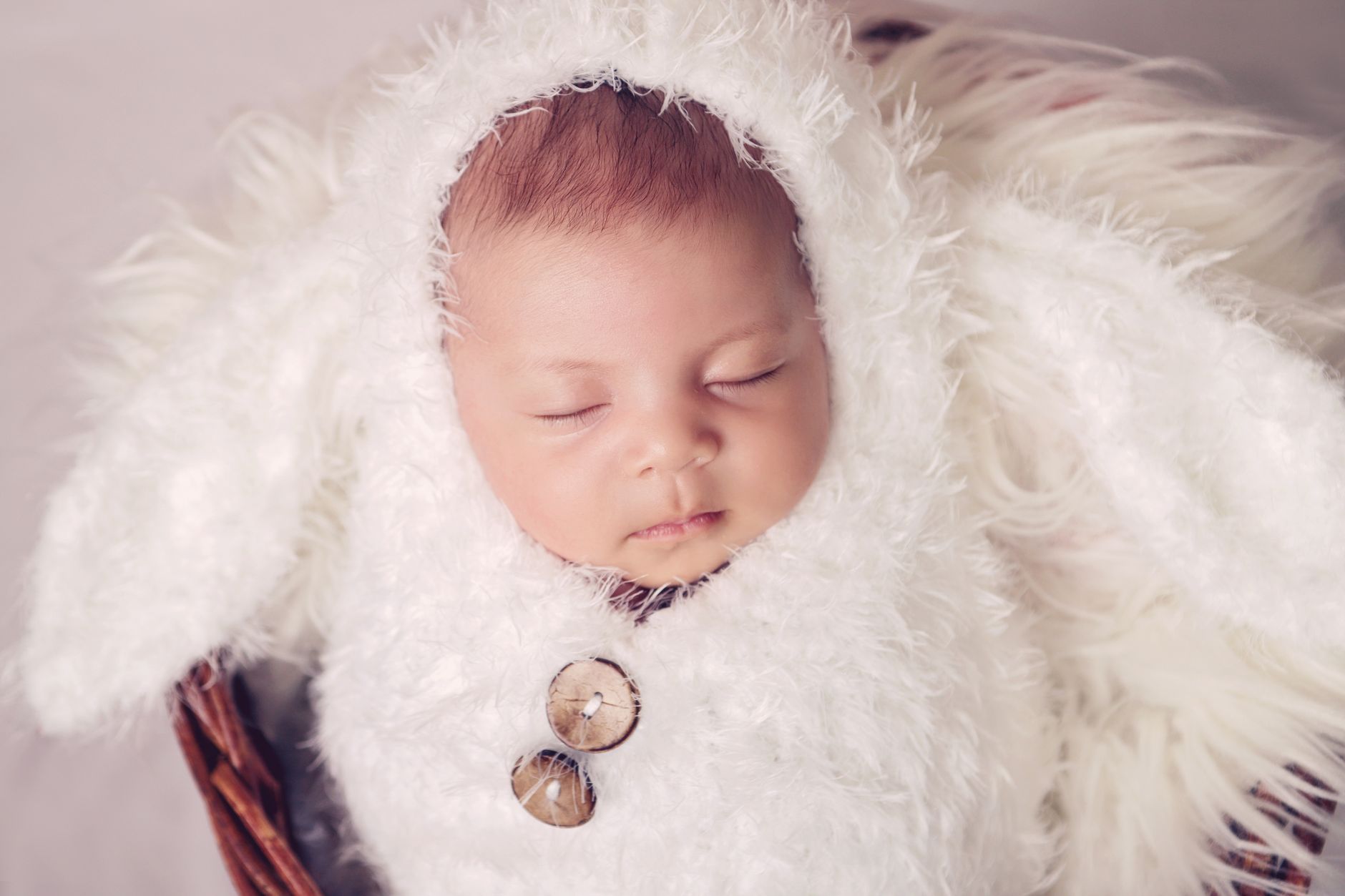 A baby smiling in a cozy sleep sack, arms free, on a soft blanket, bright and natural light