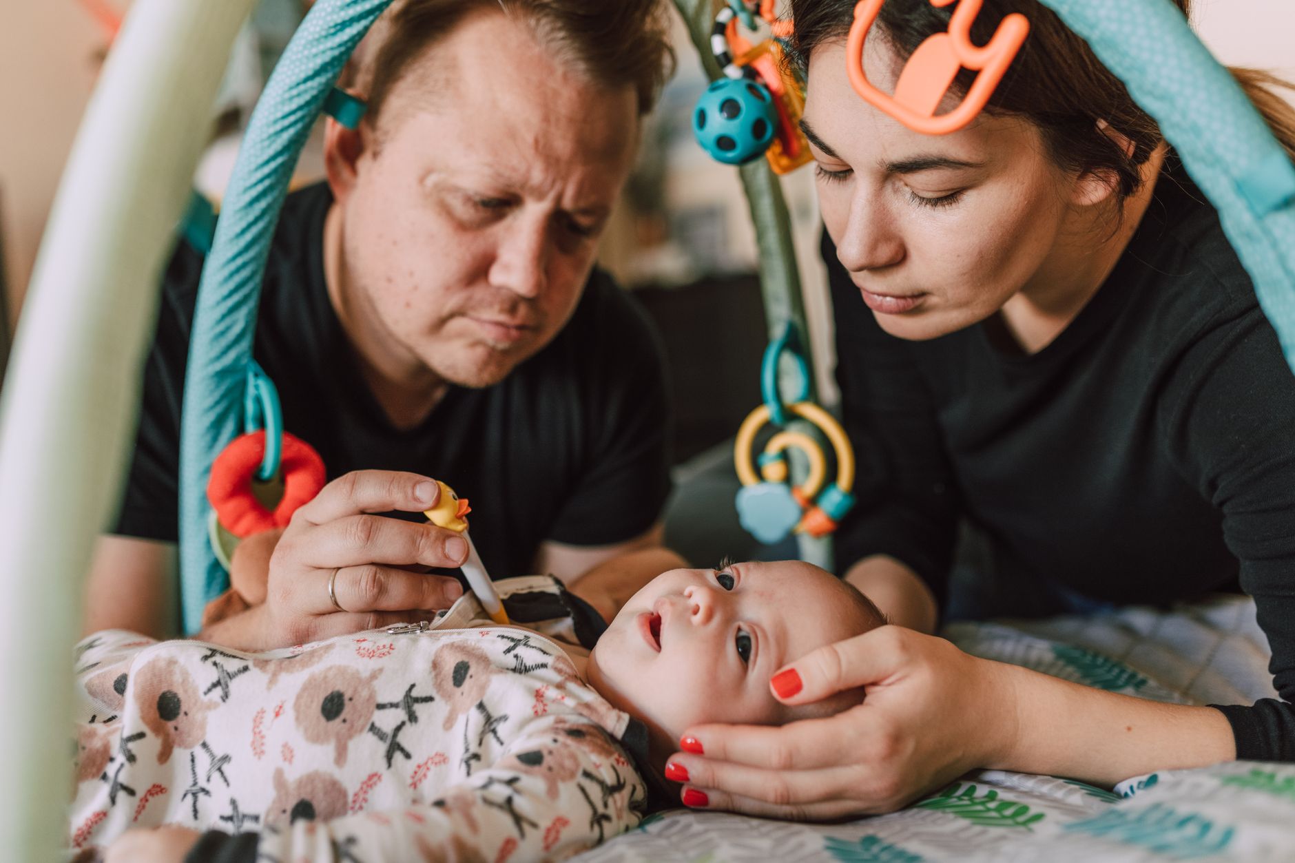 A couple sitting on the floor talking with their newborn between them
