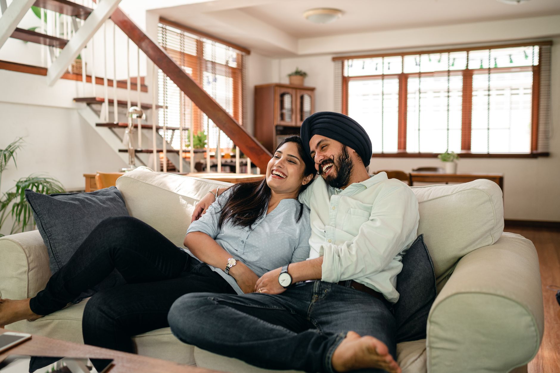A couple sitting together on a couch, holding hands while talking