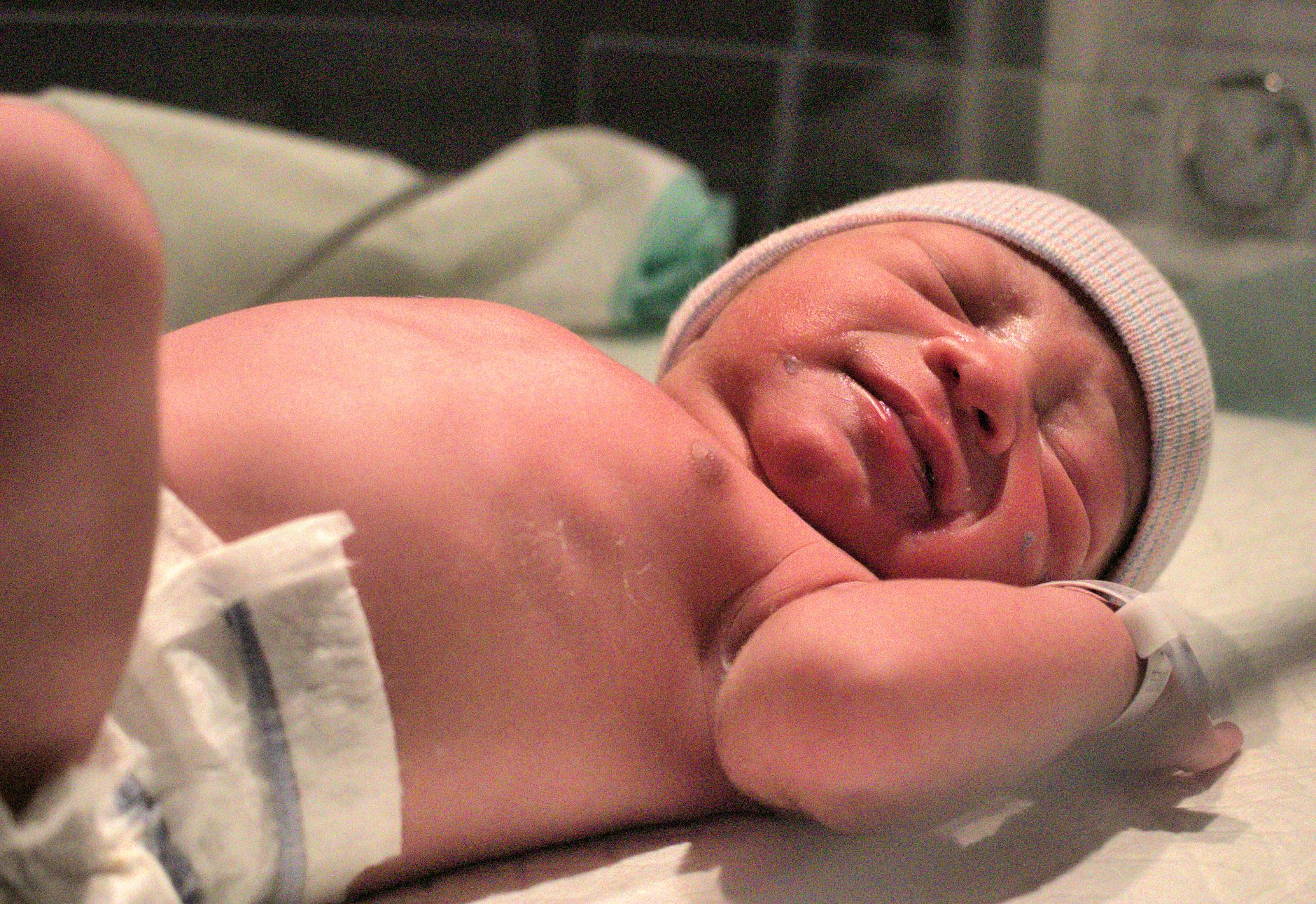 A calm hospital delivery room with a newborn on a warming table, soft natural light, and a supportive medical team