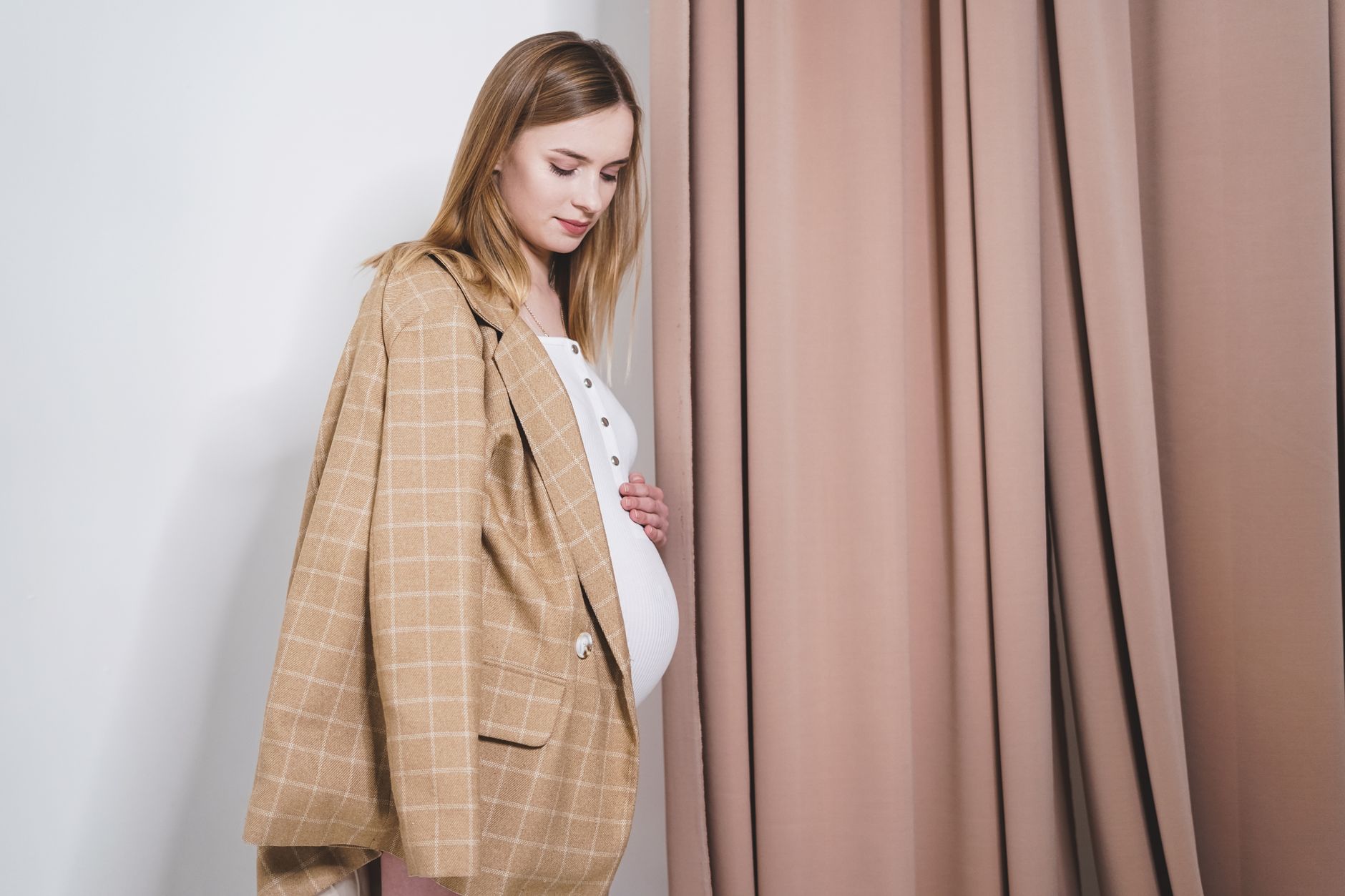 A pregnant woman gently holding her baby bump.