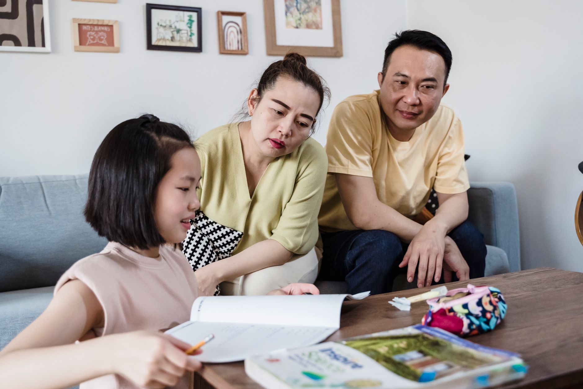A child sitting between two parents, one reading from a book of Jewish prayers and the other from a Quran, both smiling as the child points to the pages