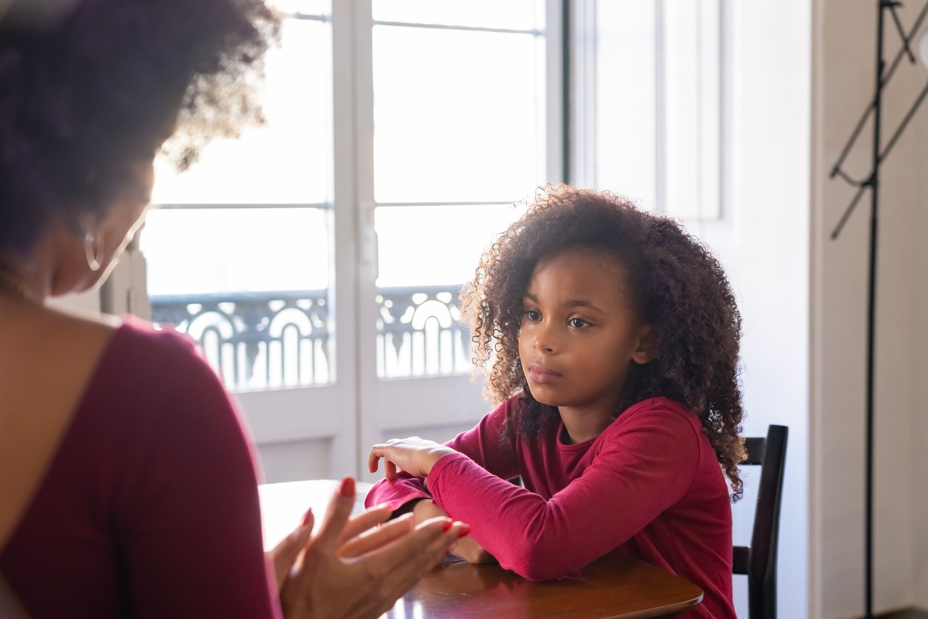 A parent and child sitting on a couch, looking at a book together, with a parent smiling and nodding as the child shares their thoughts
